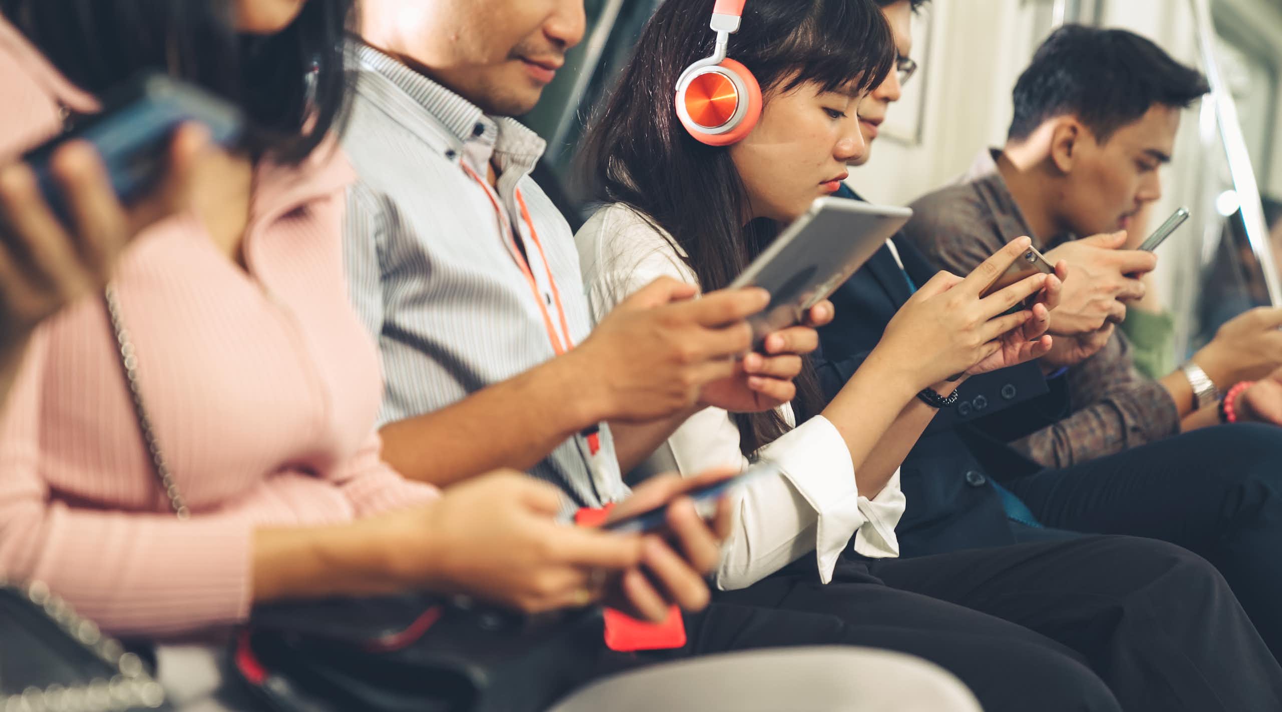 Des gens assis dans un wagon de train consultent leurs portables