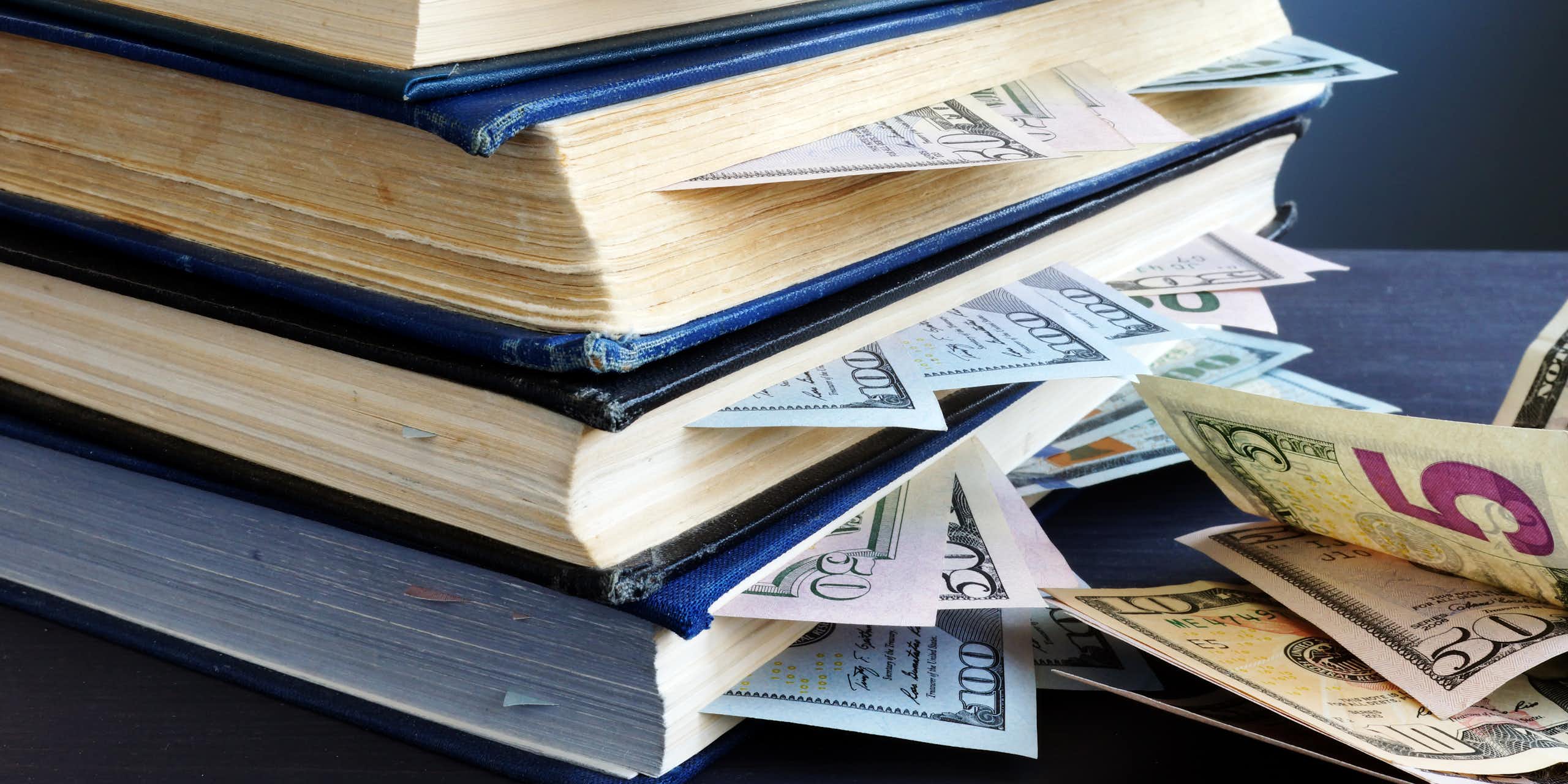 pilha de livros com notas de dólar entre suas páginas
