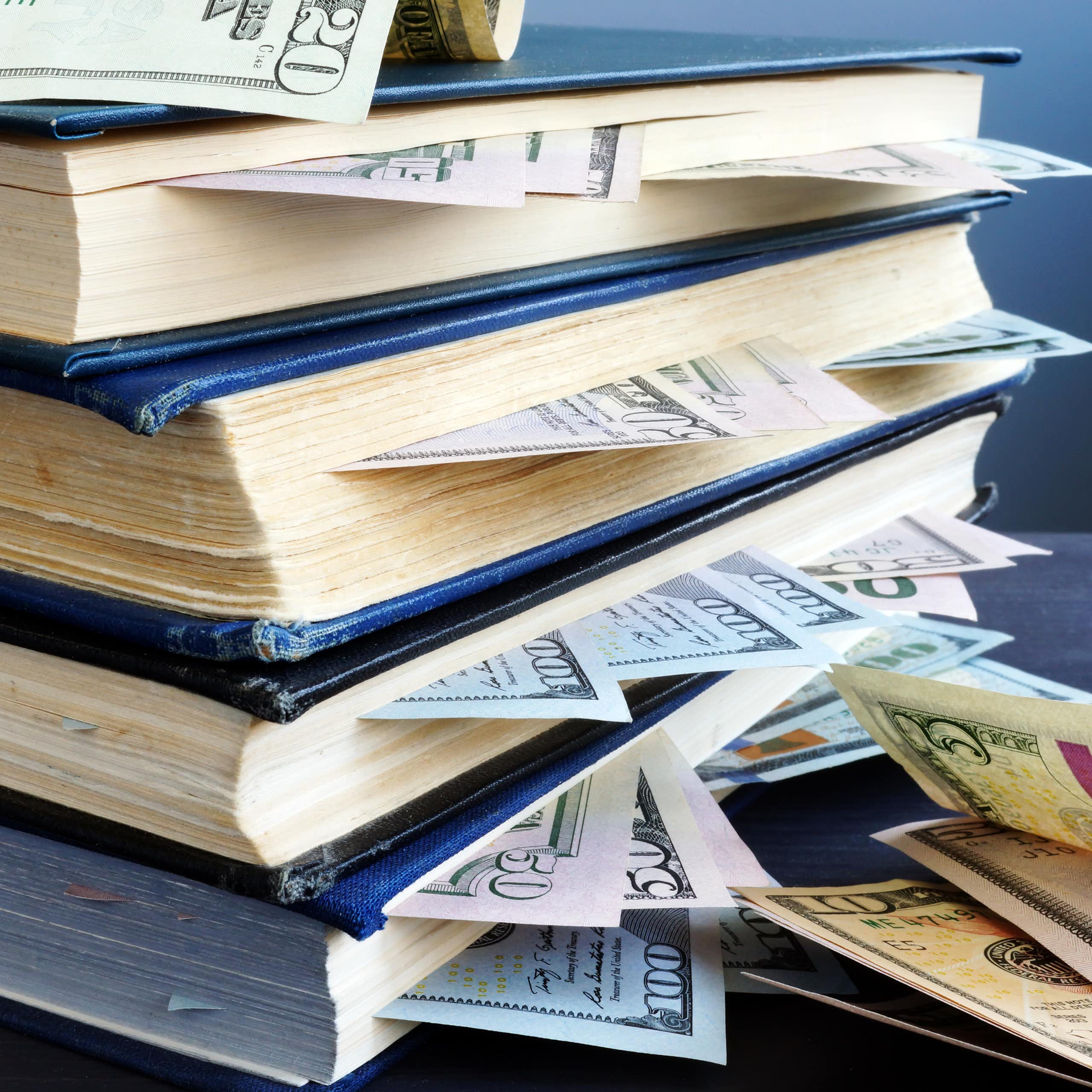 pilha de livros com notas de dólar entre suas páginas