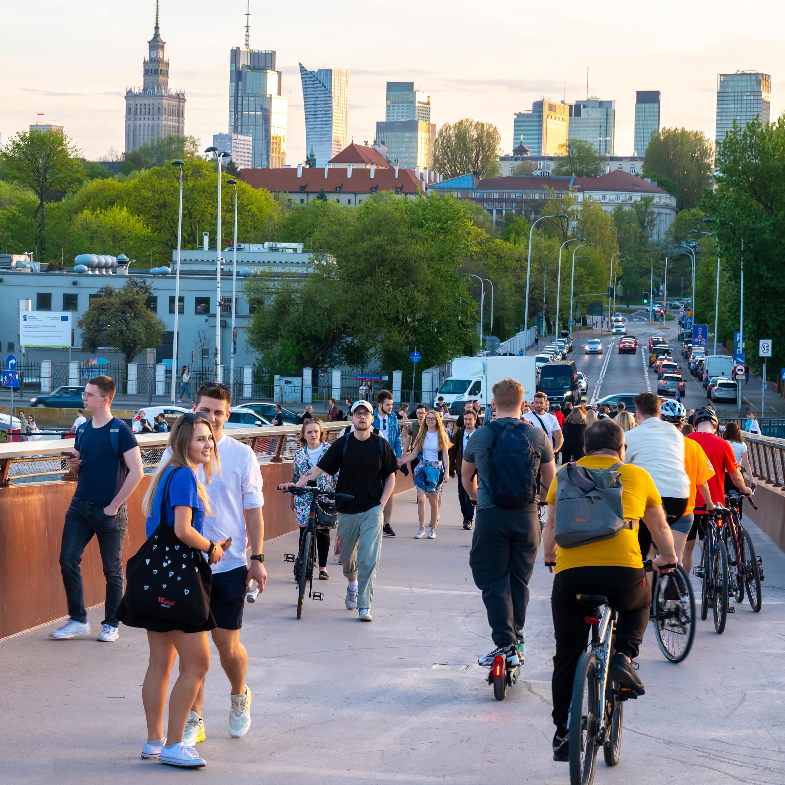 Un groupe de personnes, certaines à vélo, traversent un pont, avec des gratte-ciel à l'arrière-plan.