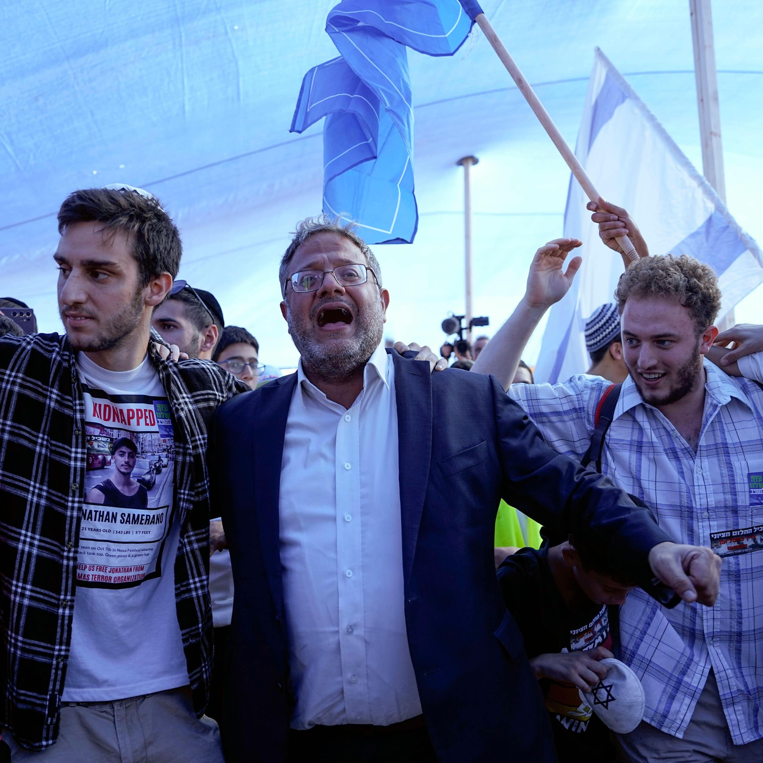 Israel's national security minister, Itamar Ben Gvir, dancing with members of the settler movement  as Israeli flags fly in the background.