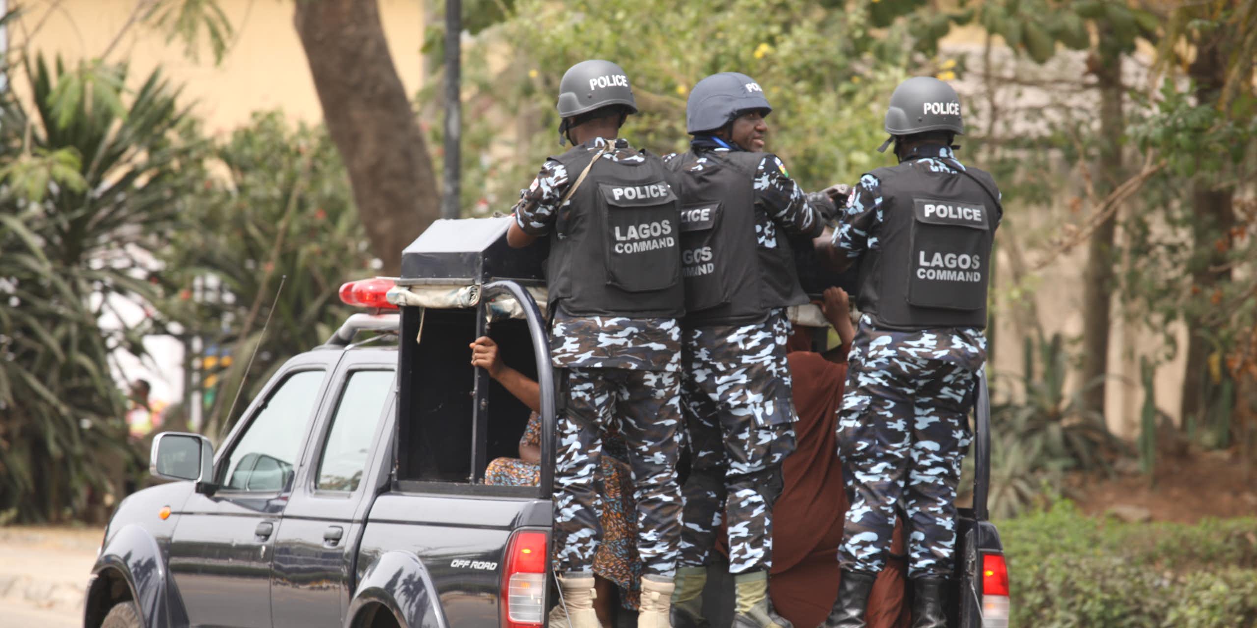 Men in police uniform hanging on the tail of van