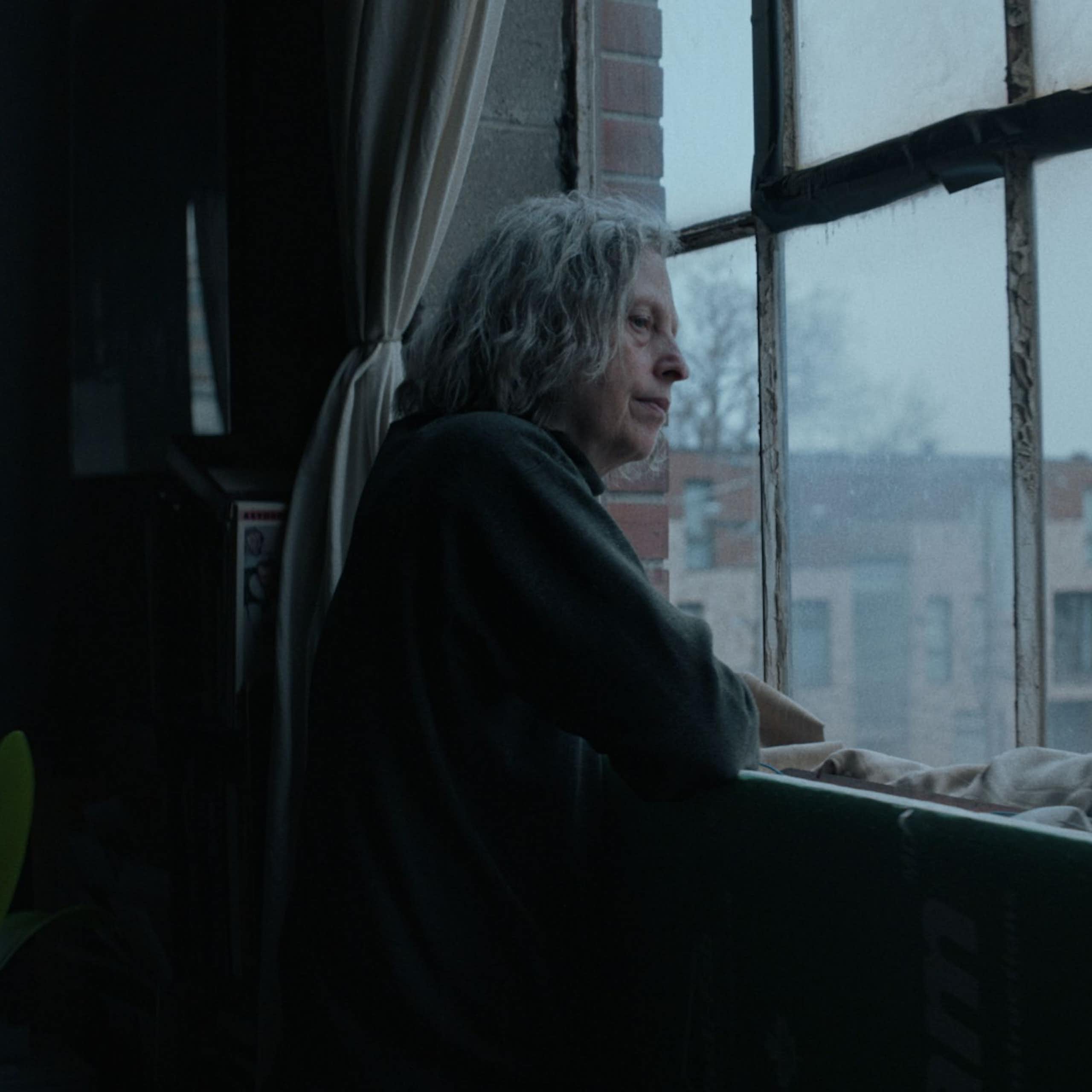 Une femme âgée regarde par la fenêtre
