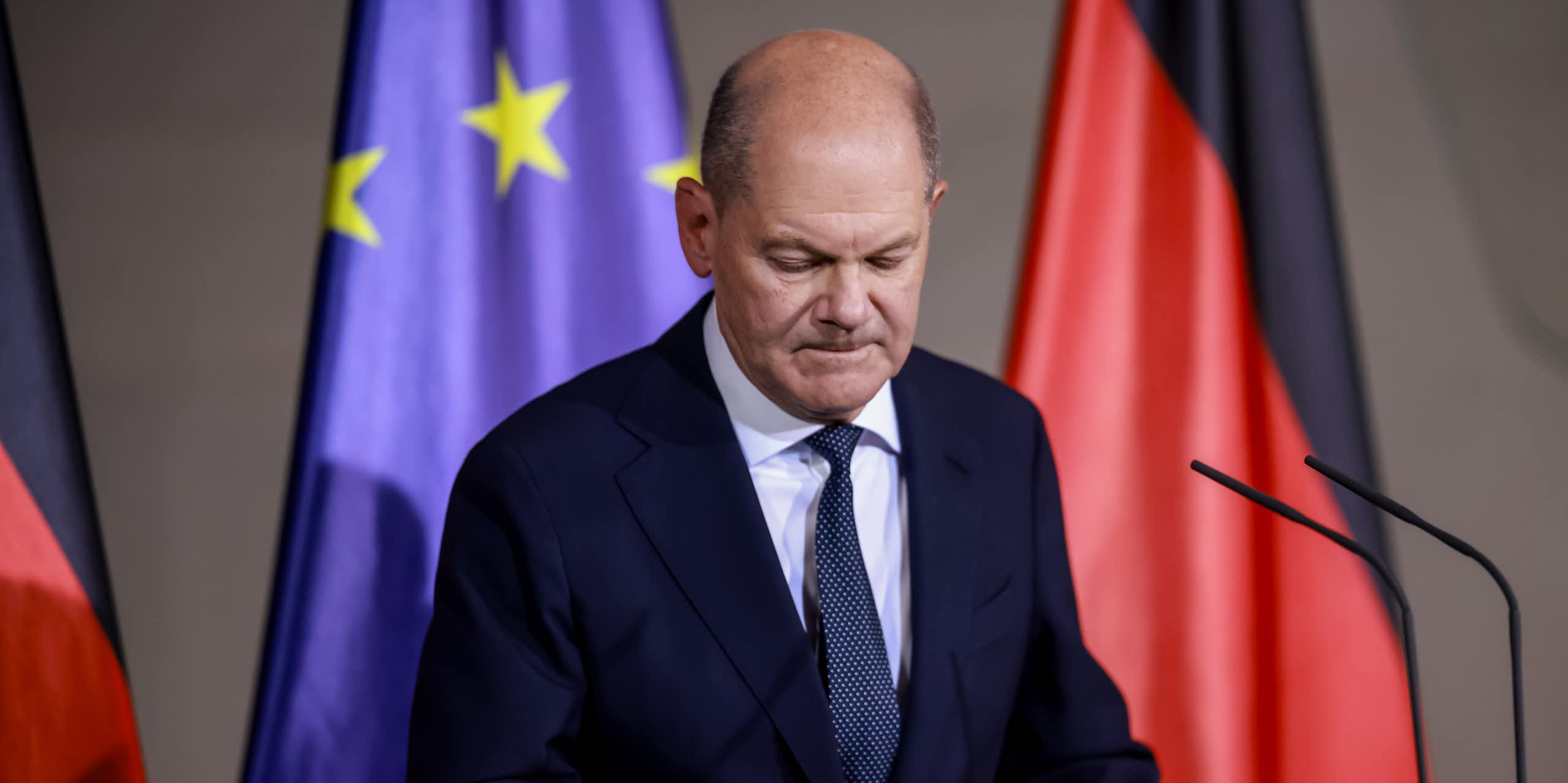 Olaf Scholz stands at a podium in front of German and EU flags