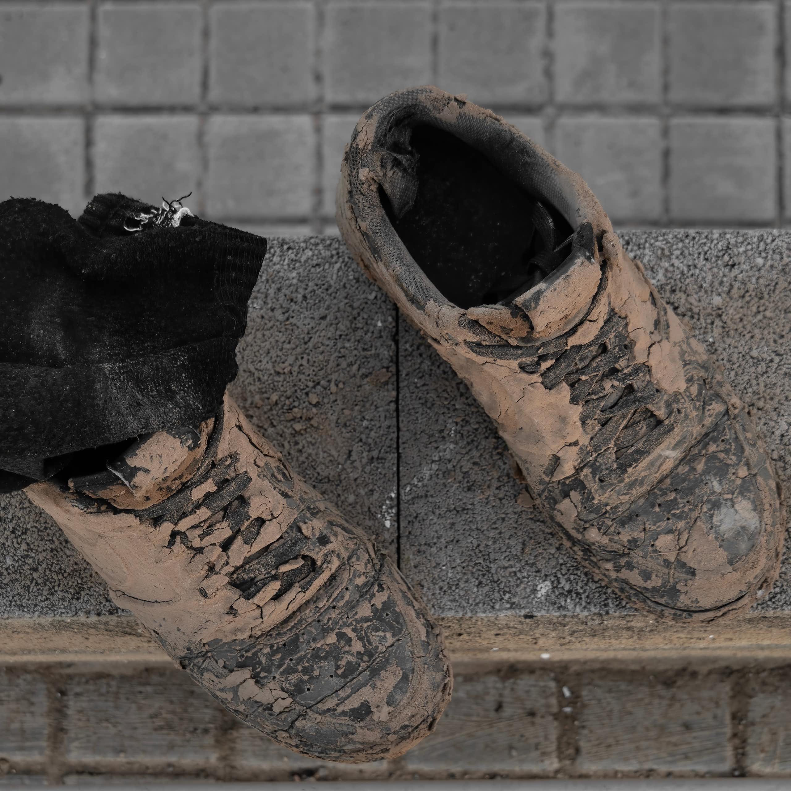 Dos botas completamente manchadas de barro.