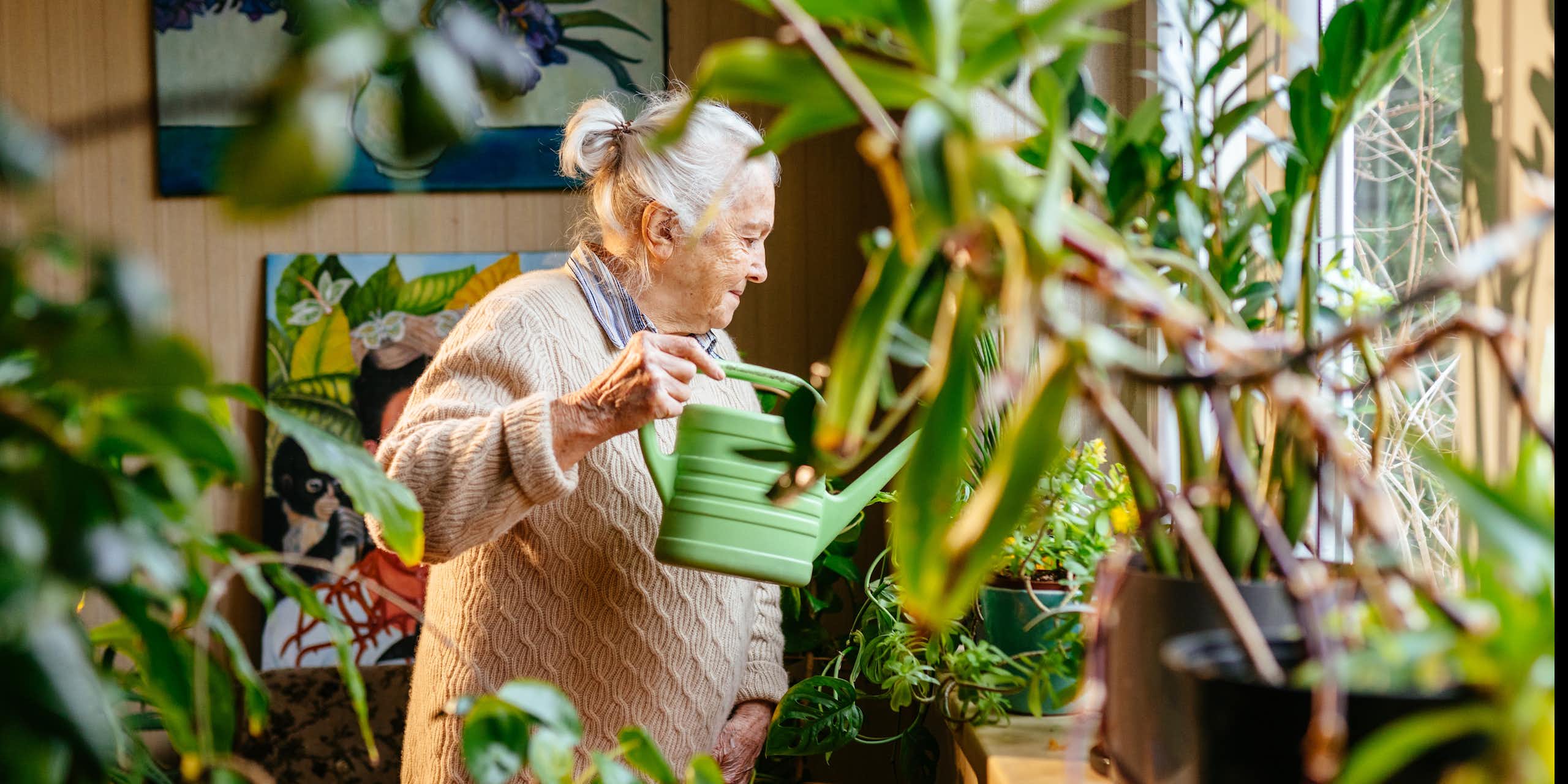 An older woman waters her plants
