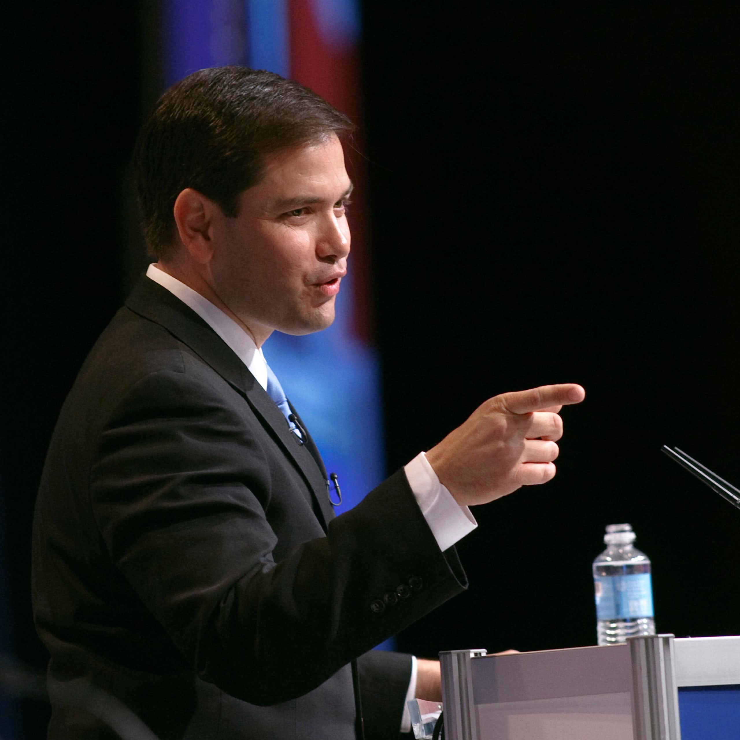 Marco Rubio in a suit with a finger pointed out.