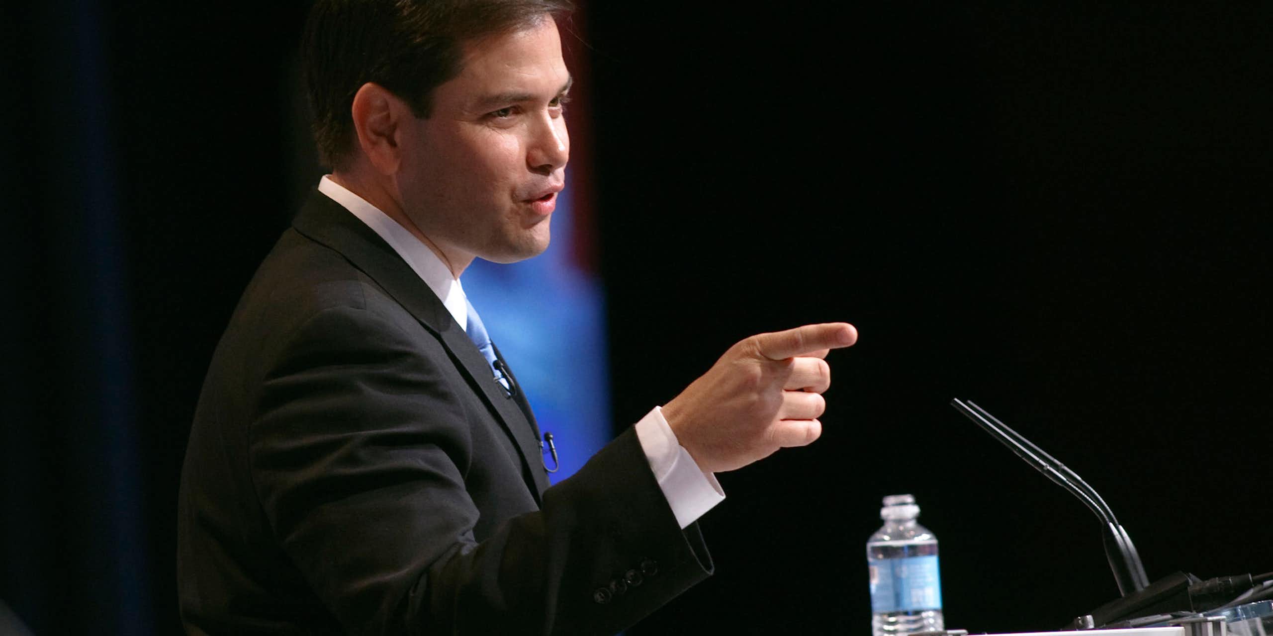 Marco Rubio in a suit with a finger pointed out.