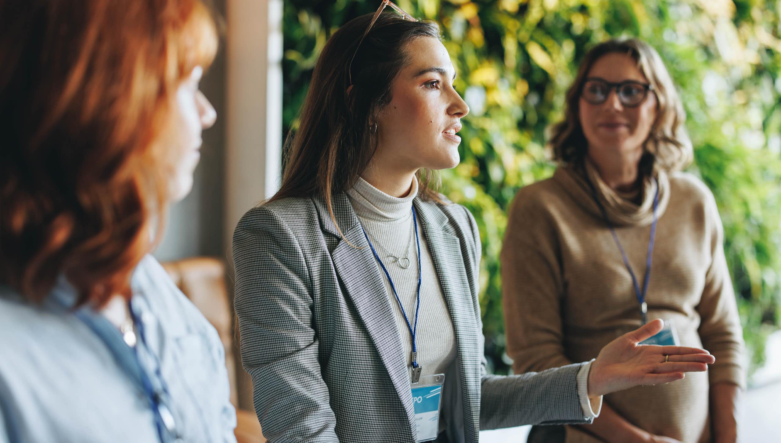 Three women wearing lanyards having a conversation