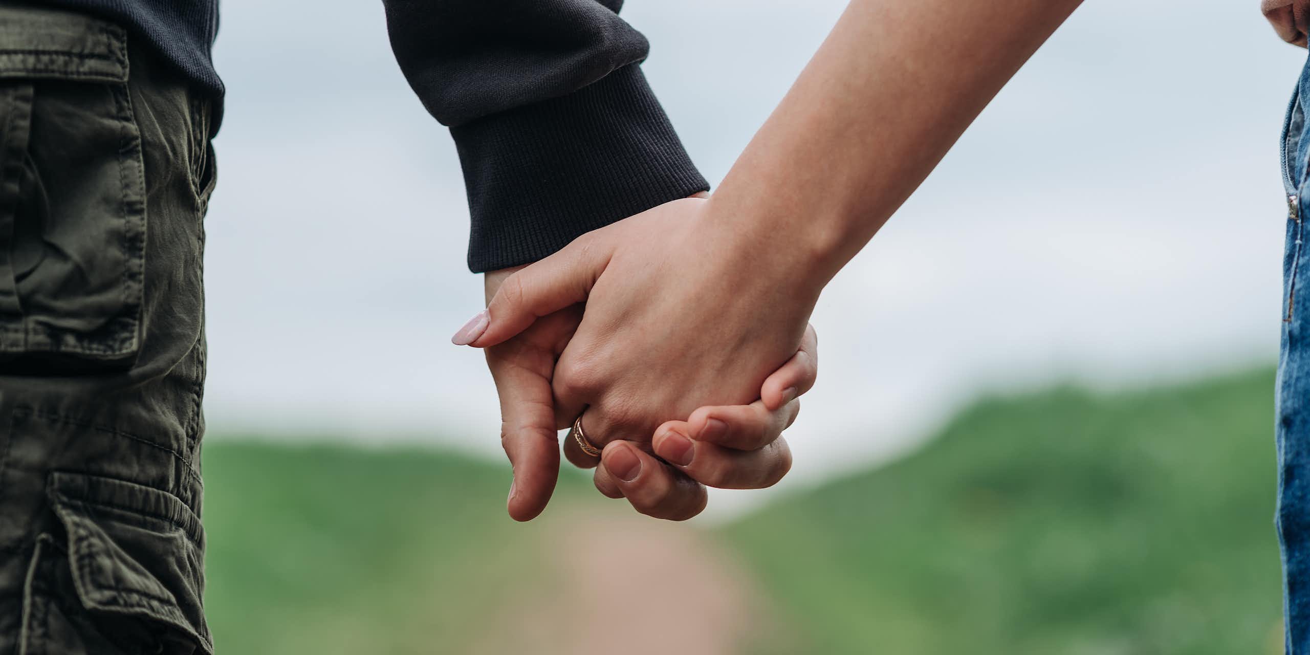 Close up of a couple holding hands walking around a path