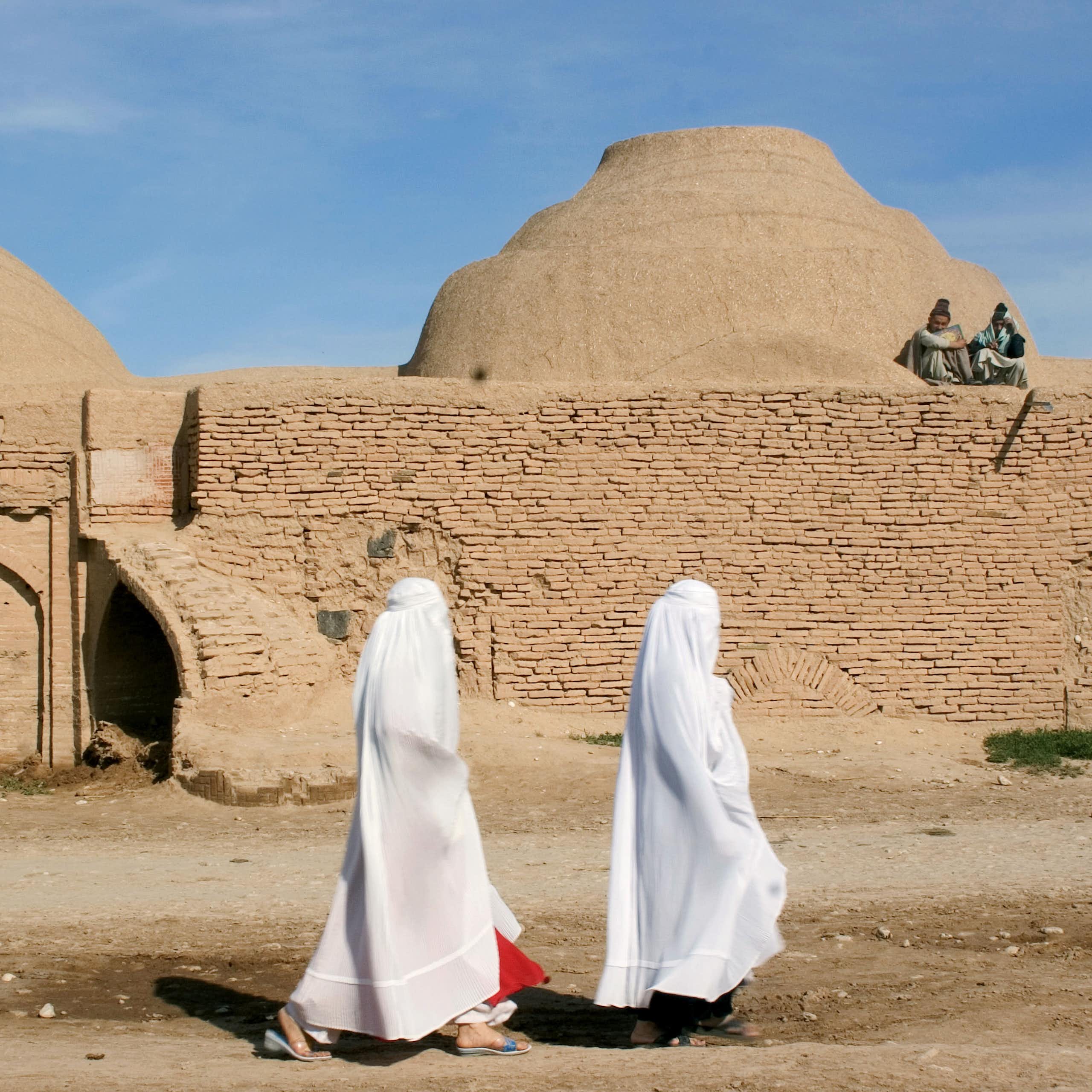 Two women walking past a madrasa.