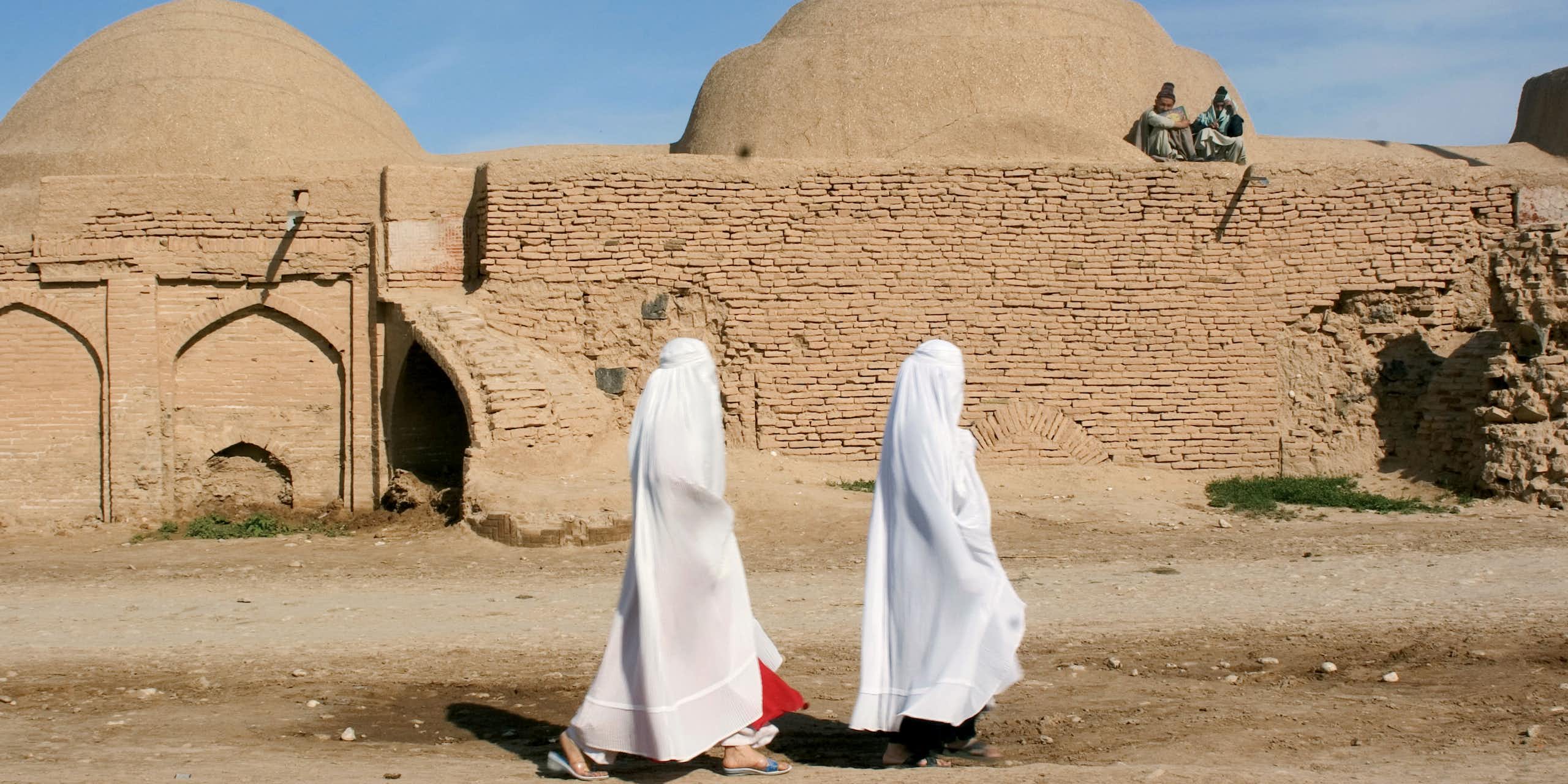 Two women walking past a madrasa.