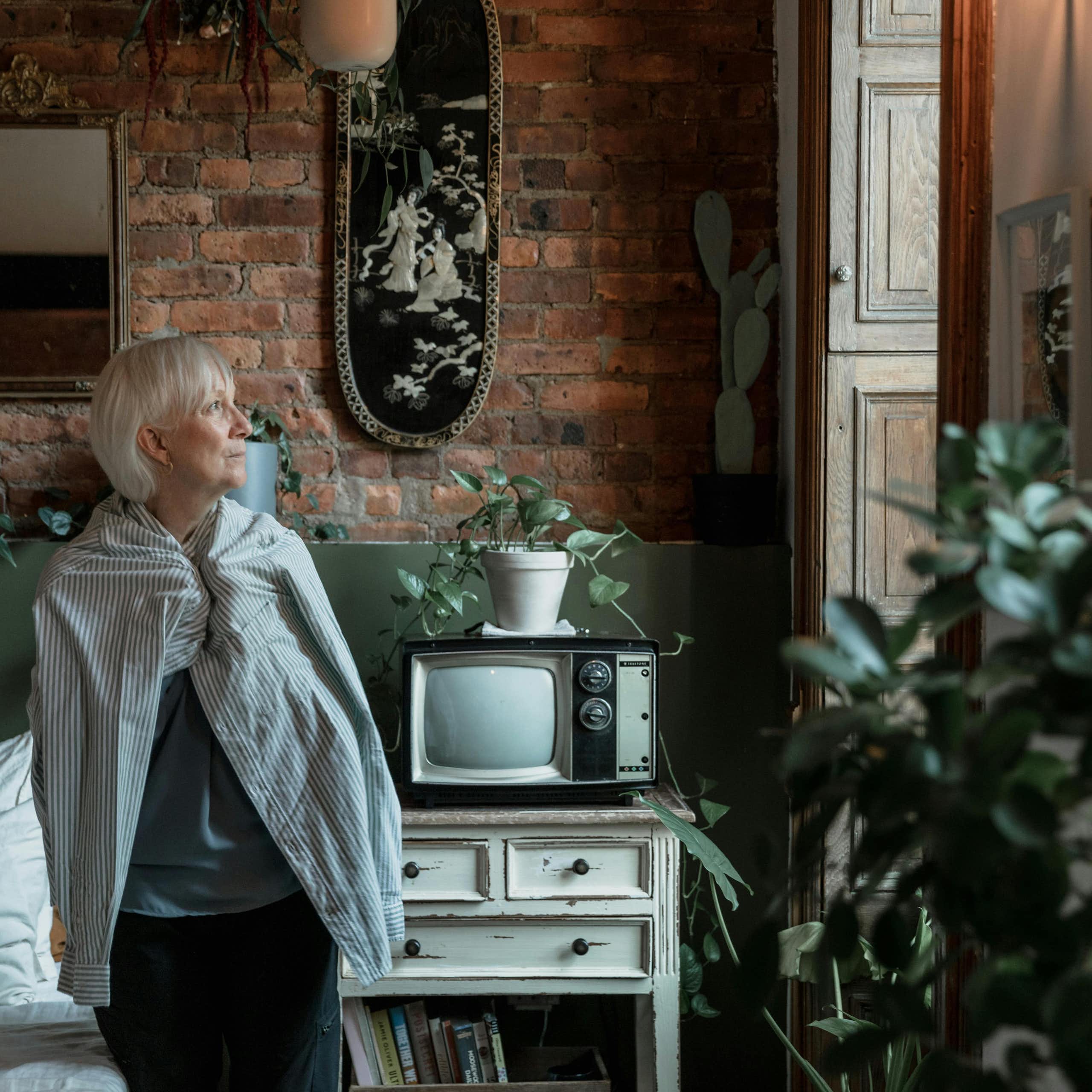 An older woman looks out the window.