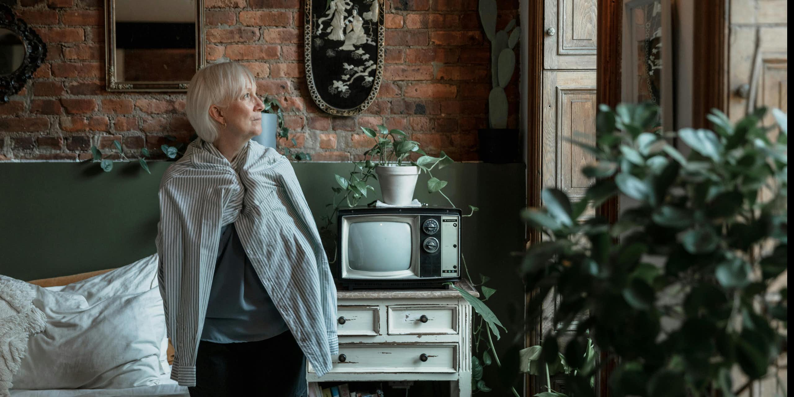 An older woman looks out the window.