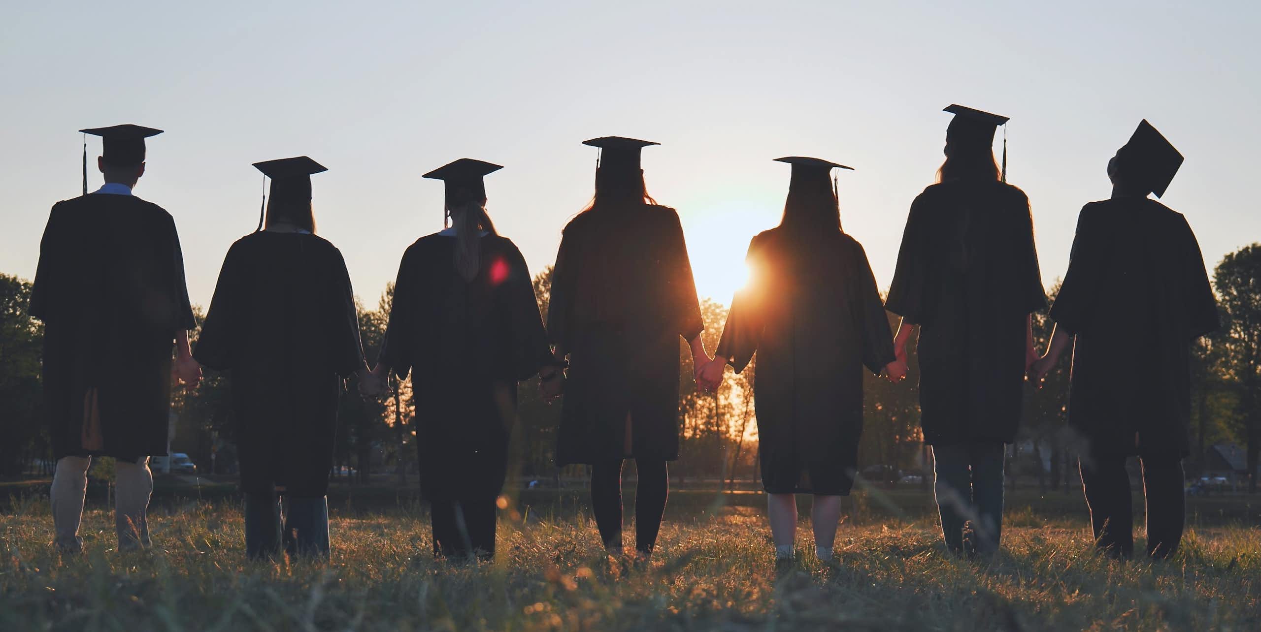 A group of graduates holding hands.