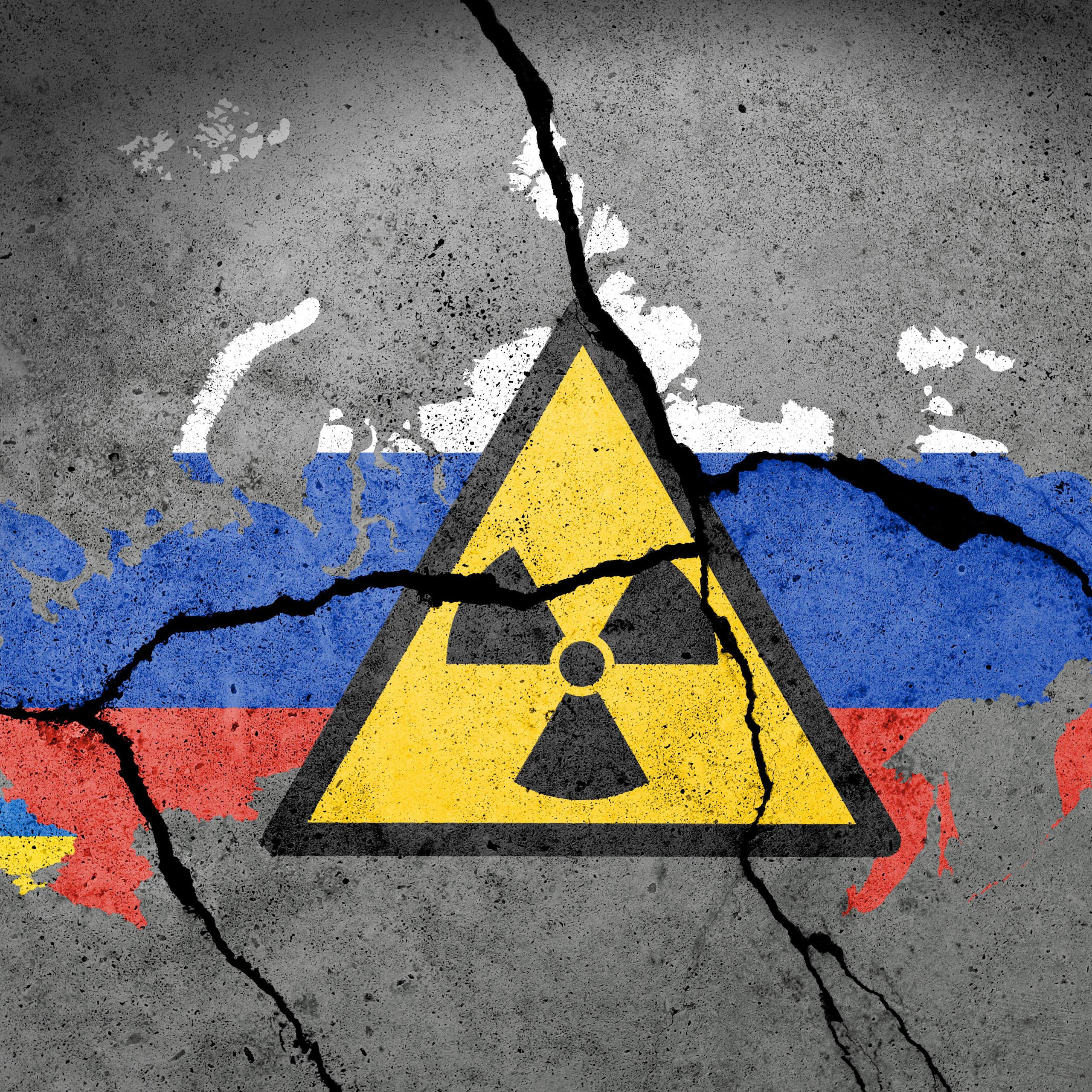 An atomic sign across a Ukrainian flag on a wall.