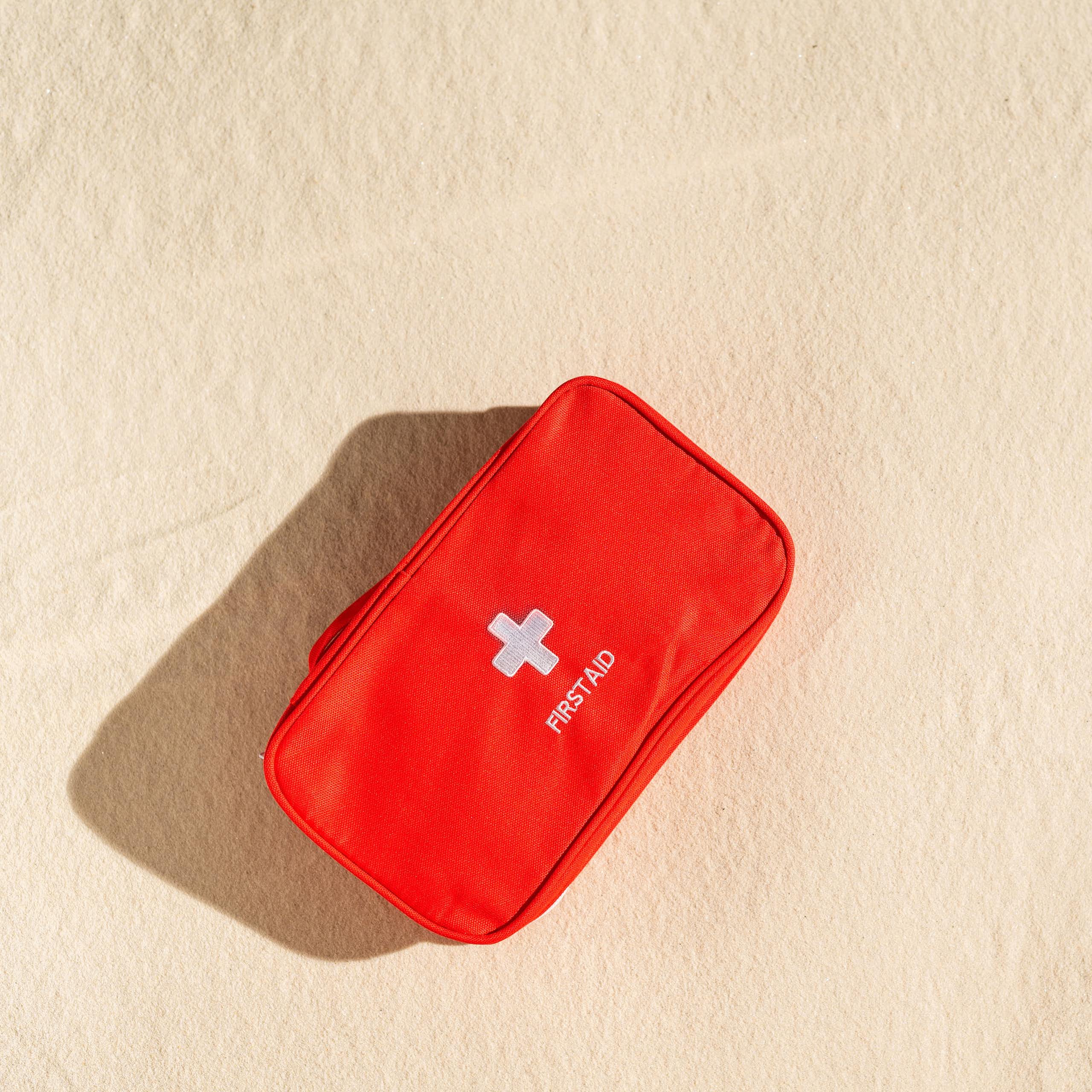 red first aid kit sits on sand