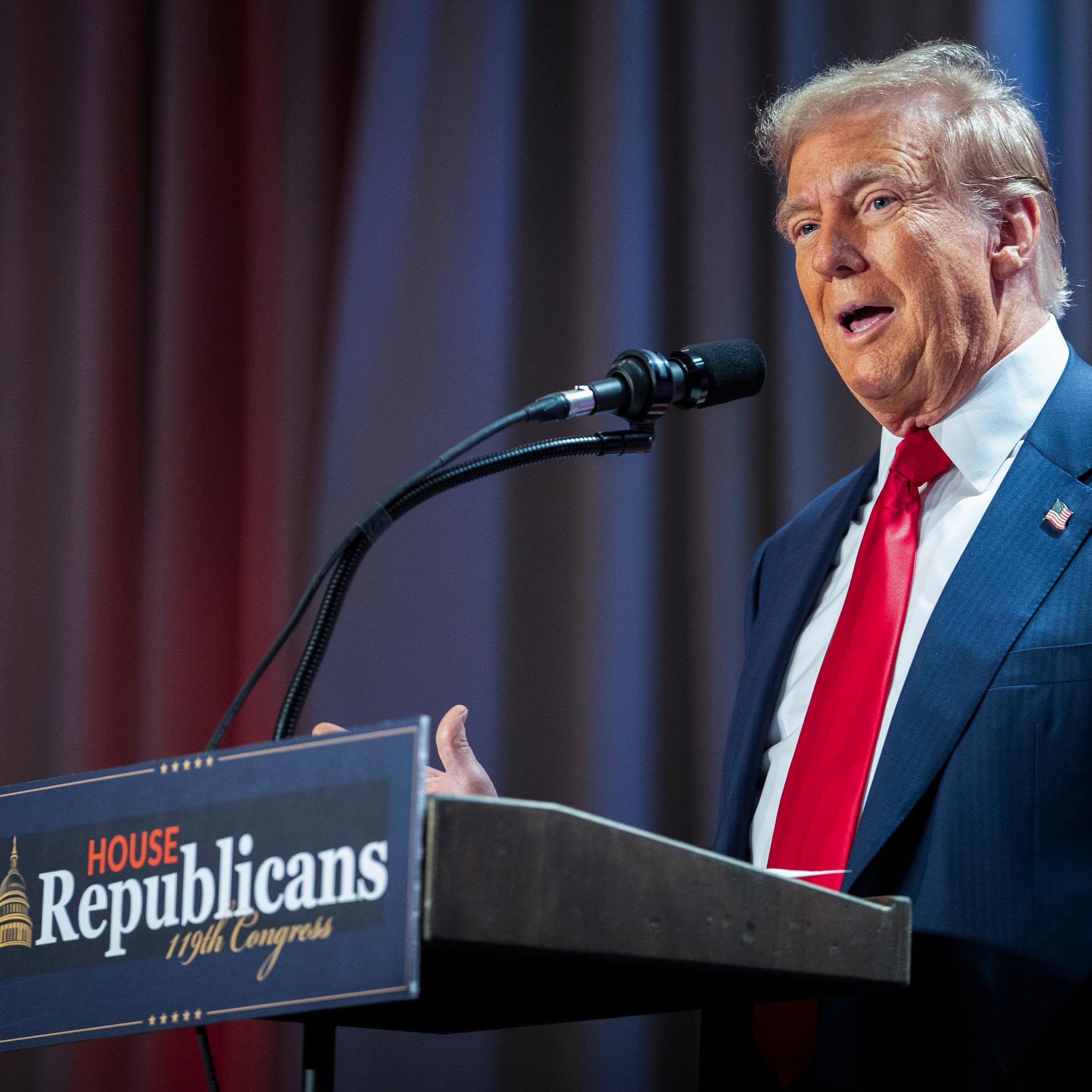 A man in a navy suit and tie gestures while speaking into a microphone on a podium that says 'House Republicans 19th Congress'