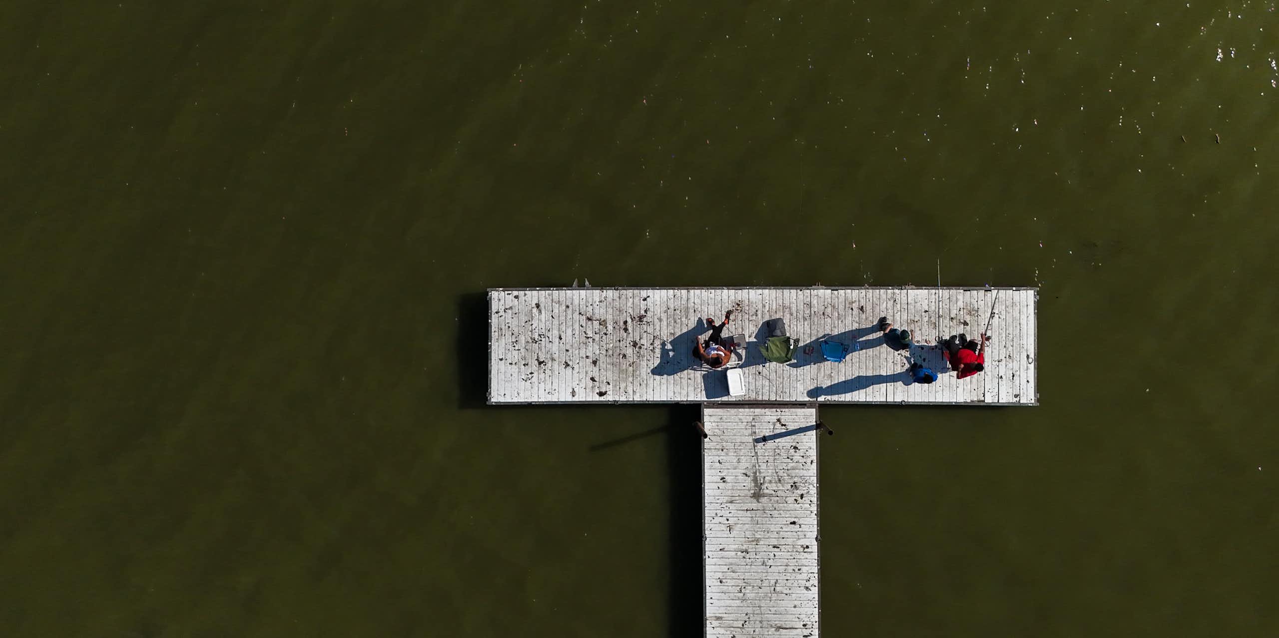 Deux personnes sont assises sur un quai entouré d'eau verte.