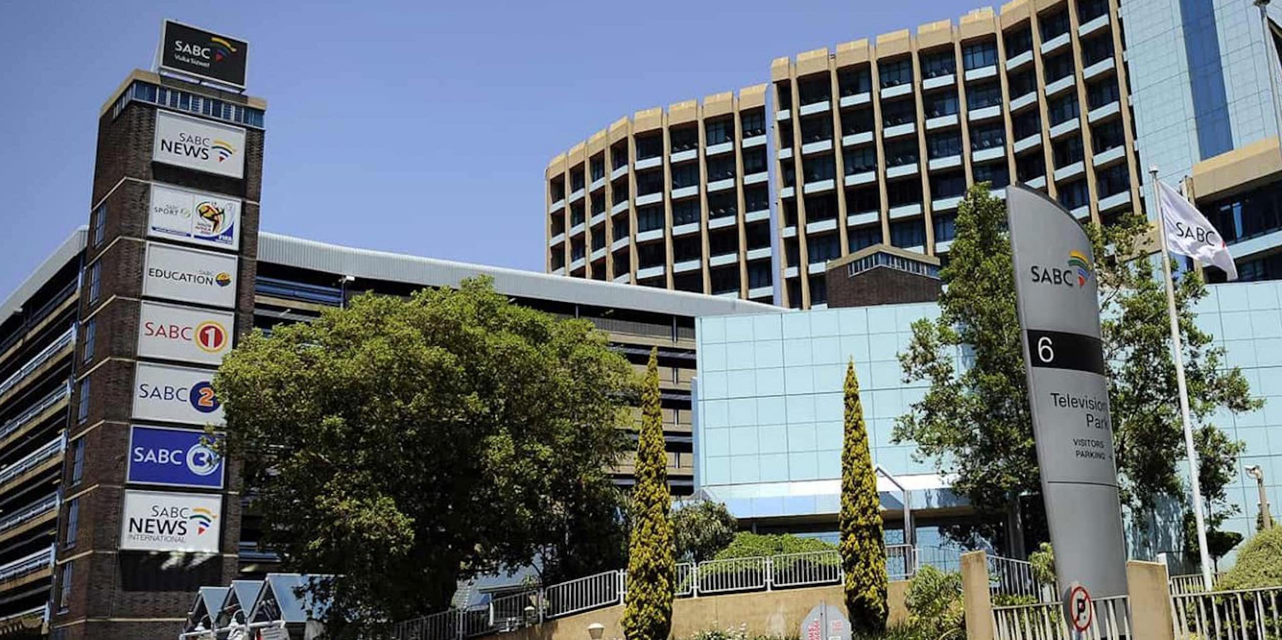 Building with South African and SABC flags outside, and boards with names of several news channels.