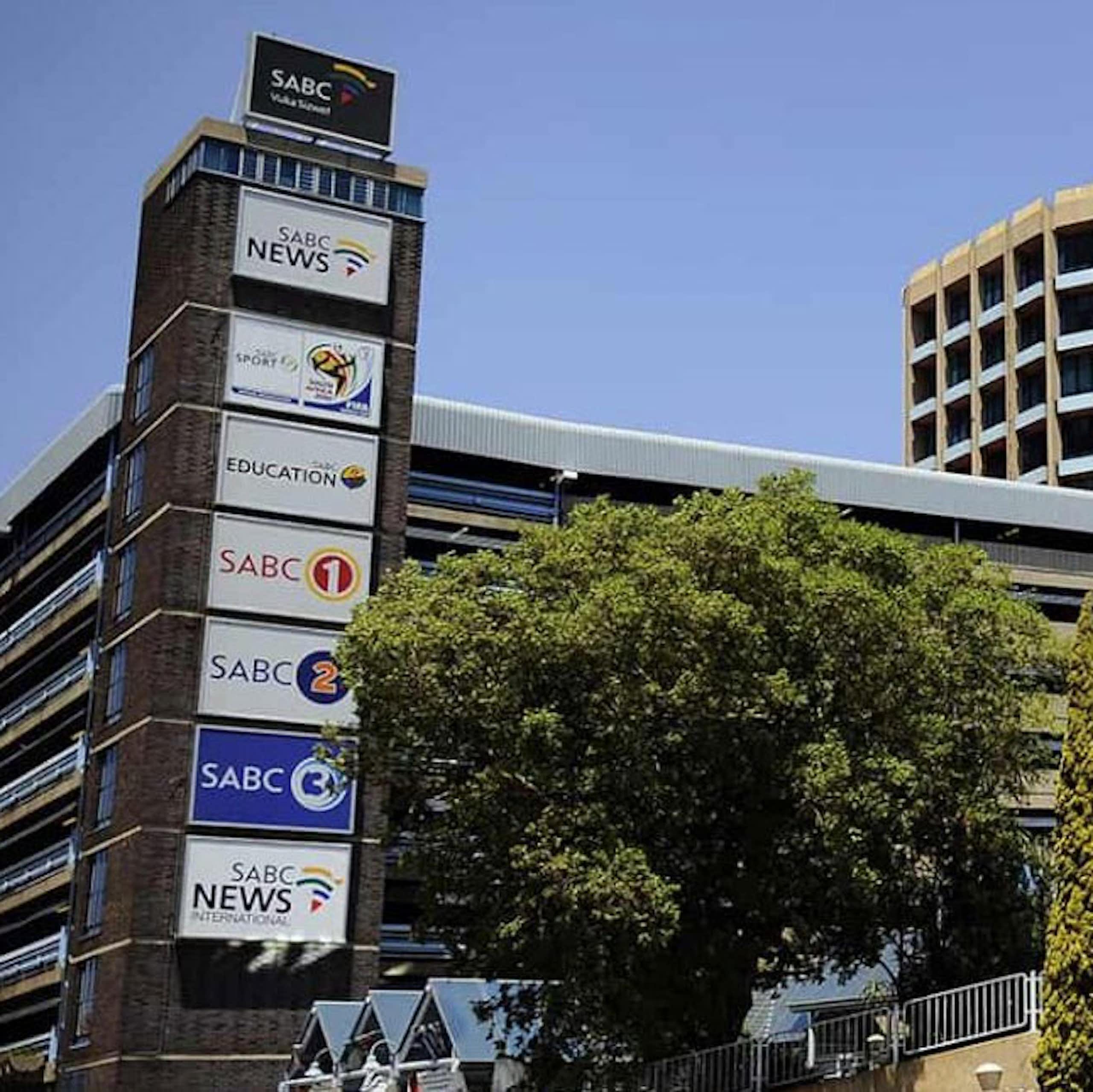 Building with South African and SABC flags outside, and boards with names of several news channels.