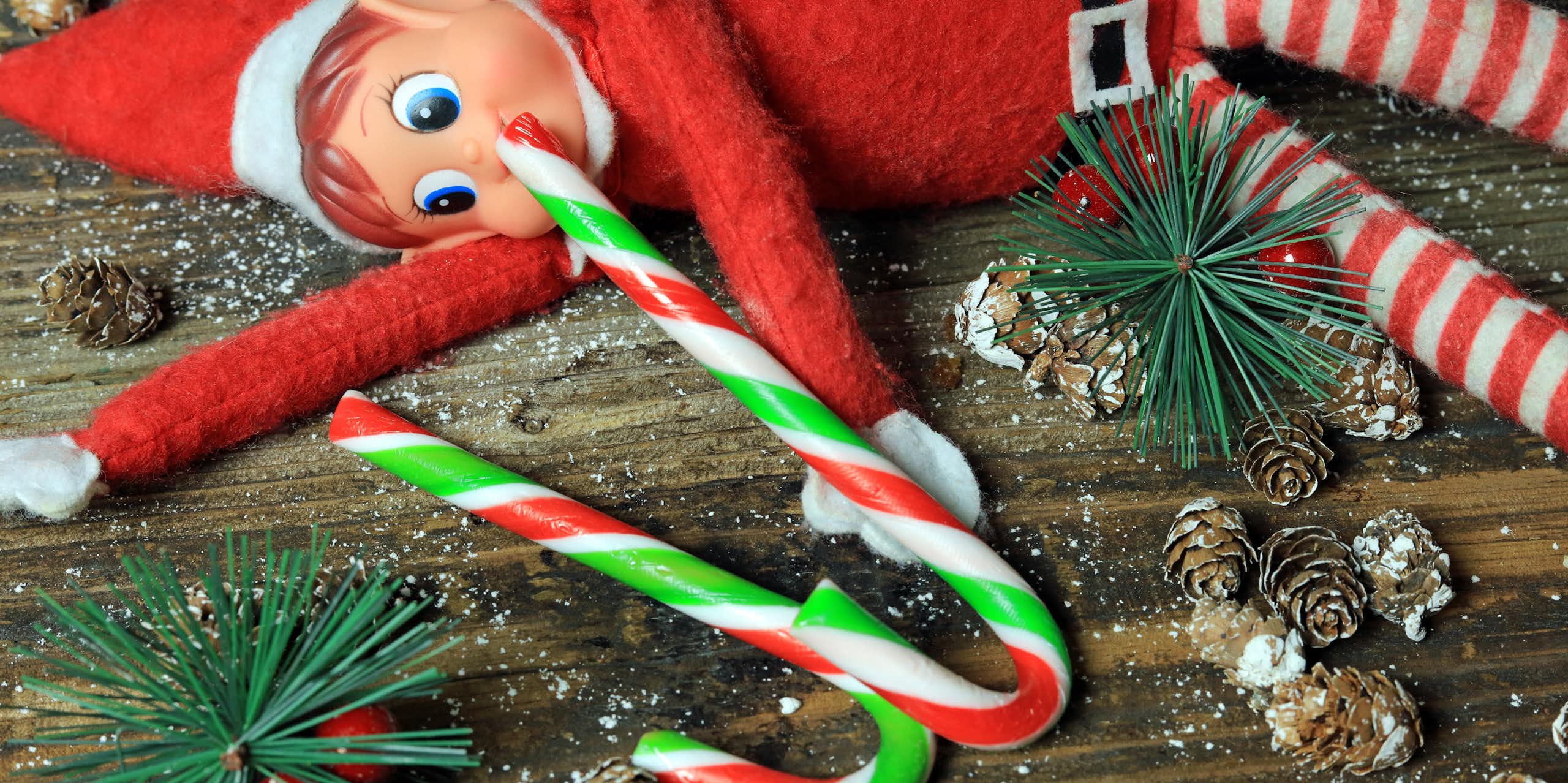 elf toy posed with candy canes on table