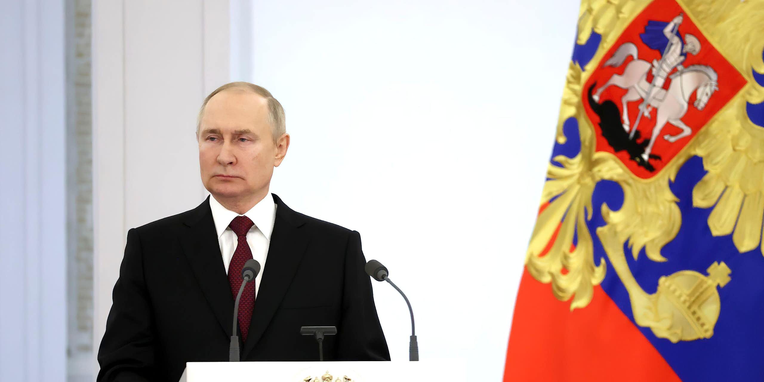 President Putin at a podium next to a Russian flag.