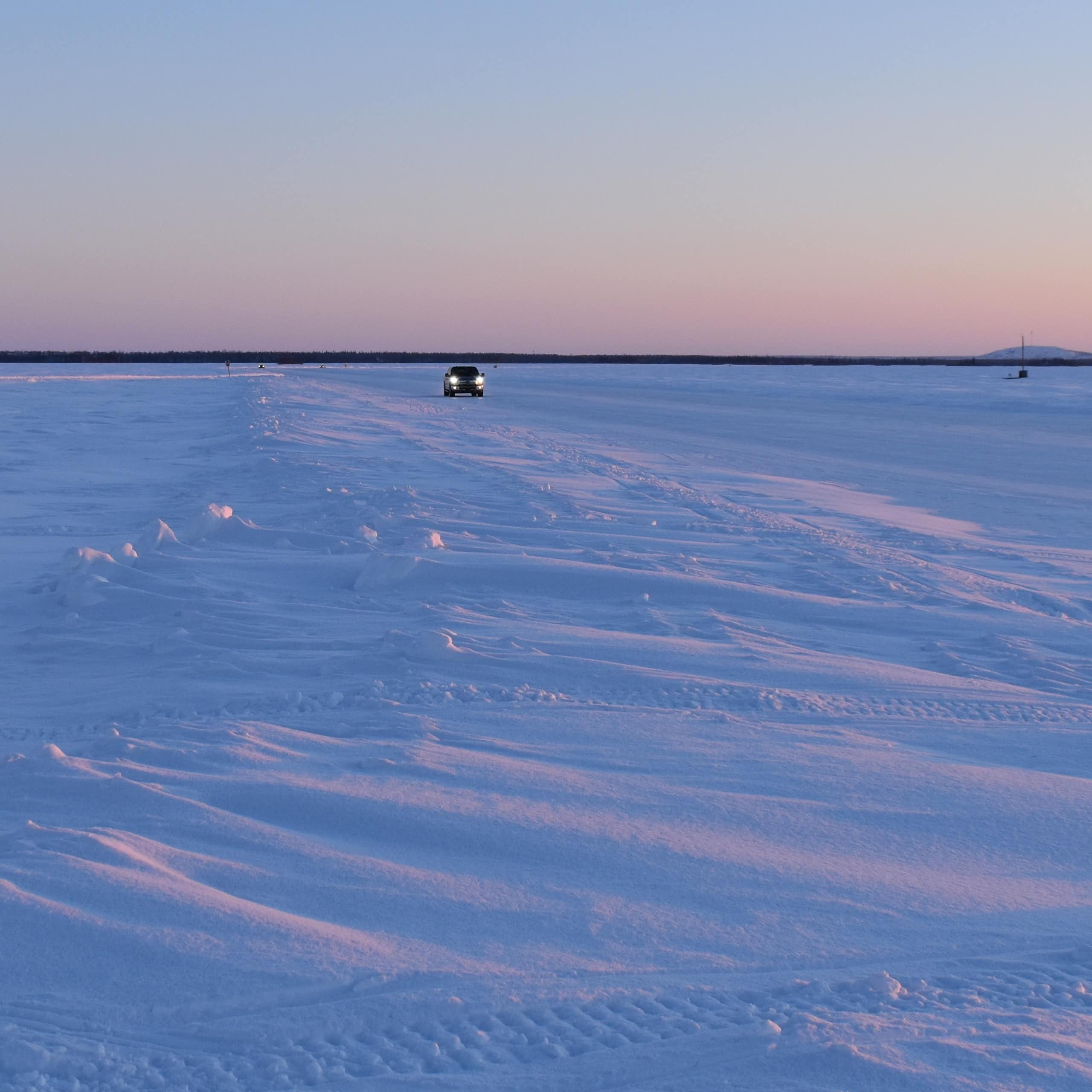 A car drives across an ice road.
