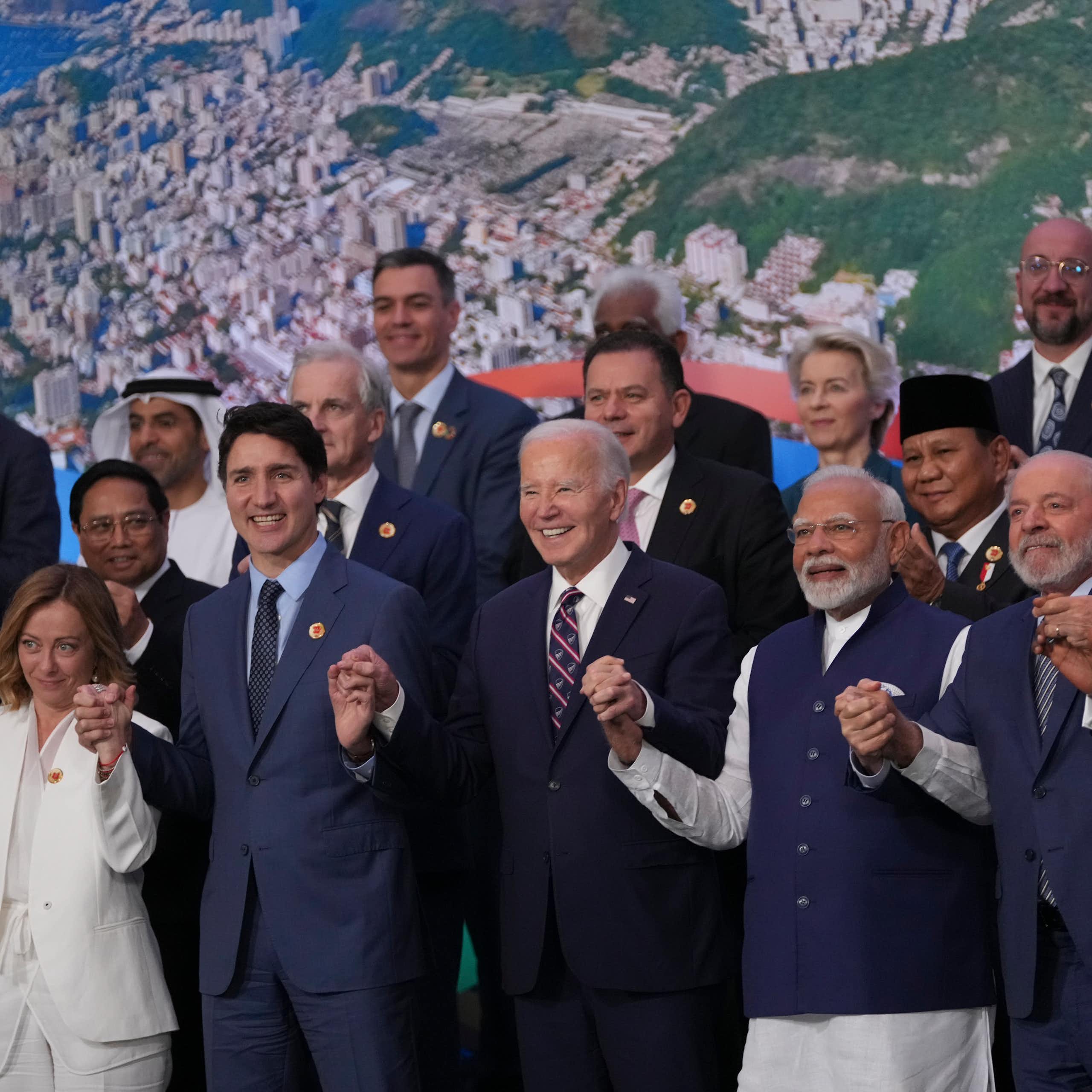 Des personnes debout se tiennent par la main en souriant devant une image de la ville de Rio de Janeiro