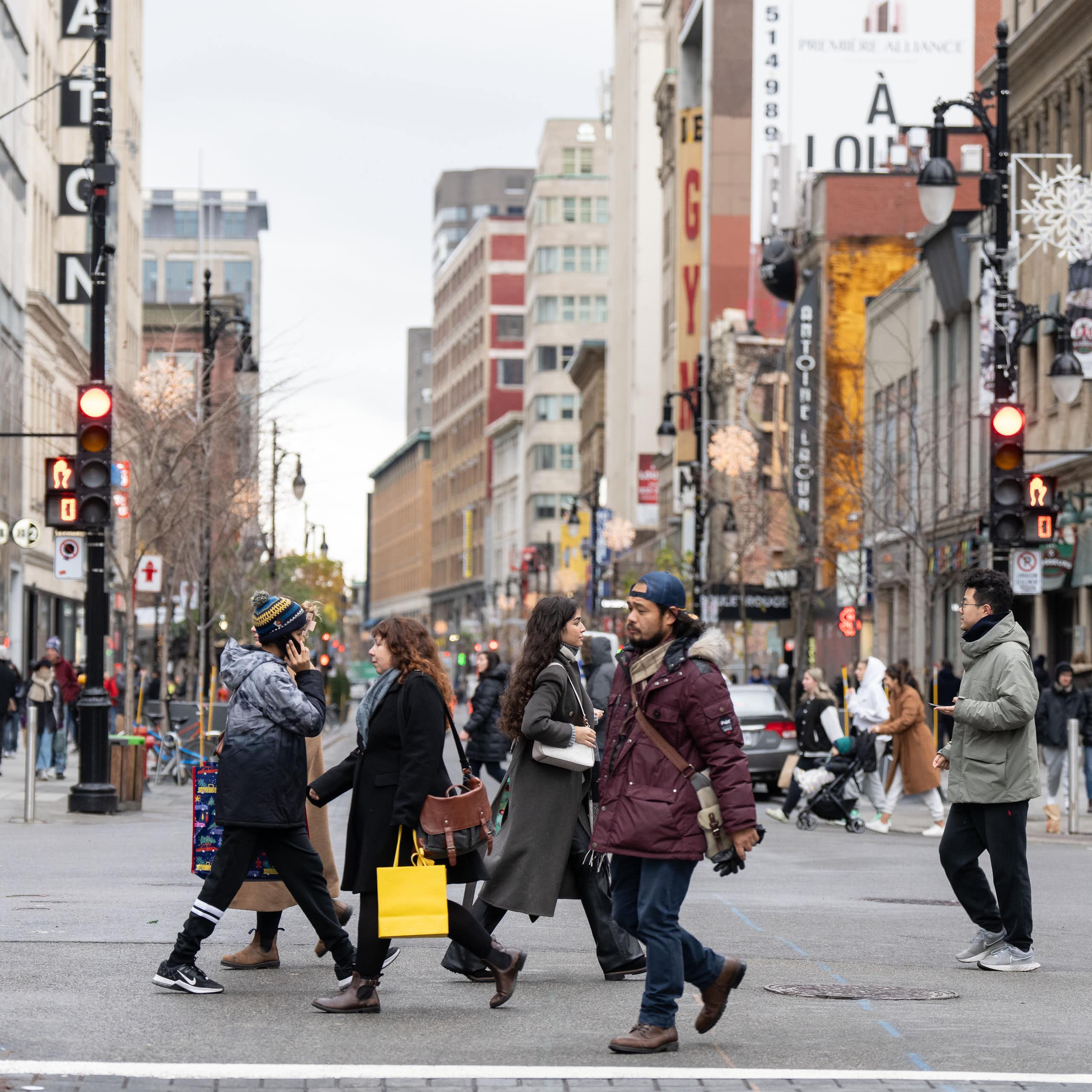 Shoppers holding shopping bags cross a street intersection