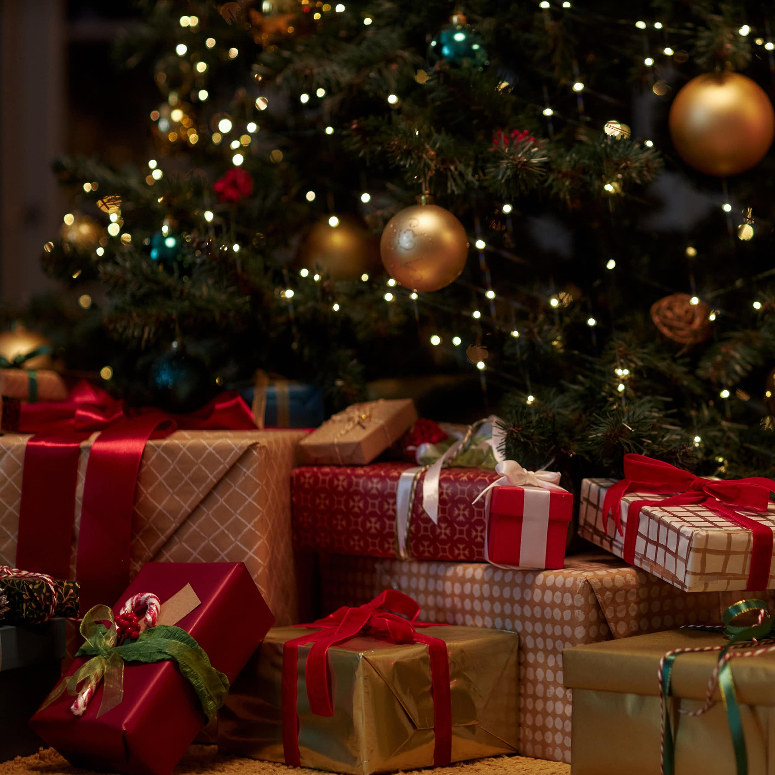des cadeaux emballés au pied d'un sapin avec des décorations de Noël