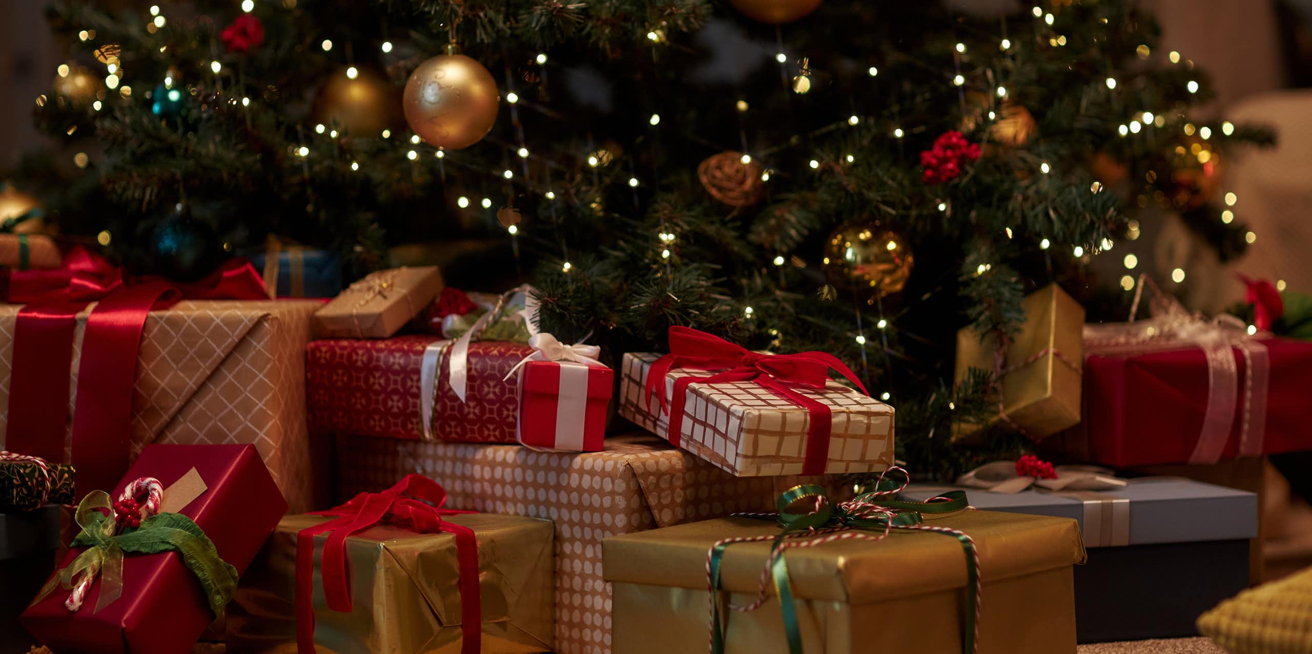 des cadeaux emballés au pied d'un sapin avec des décorations de Noël