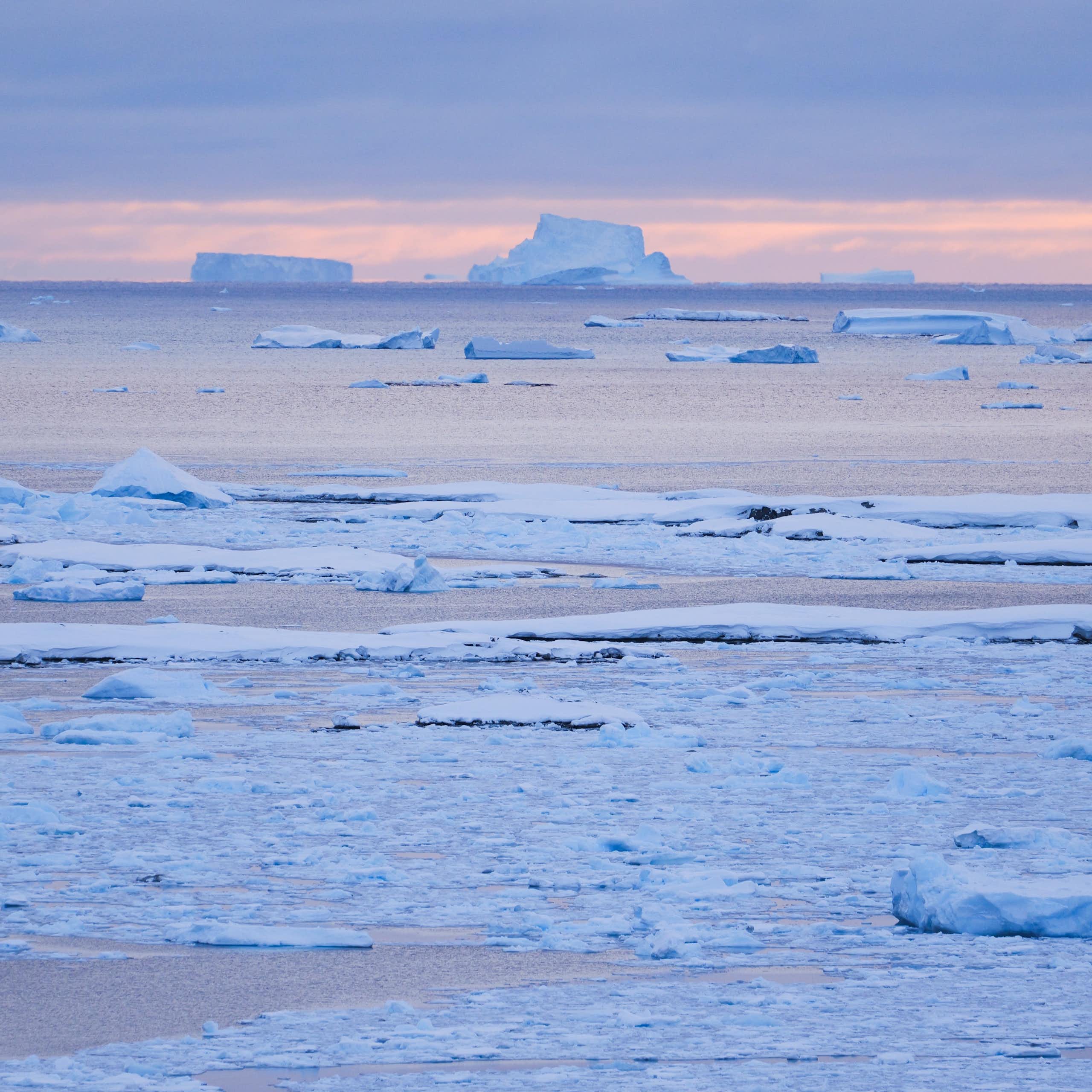 imagem de um oceano gelado com icebergs ao fundo