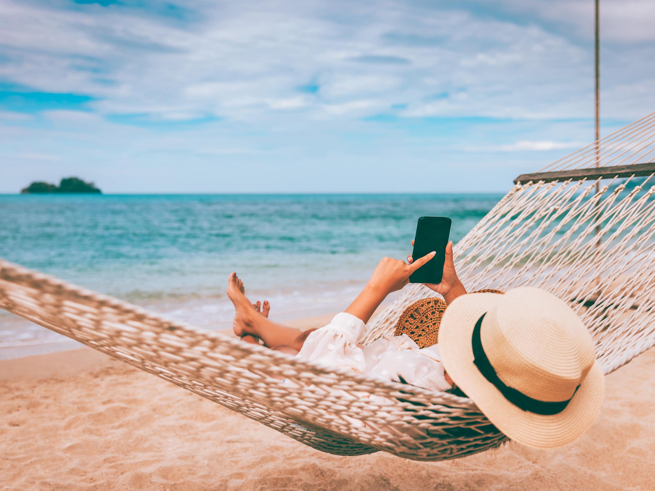 Woman wearing hat lying on a hammock at the beach