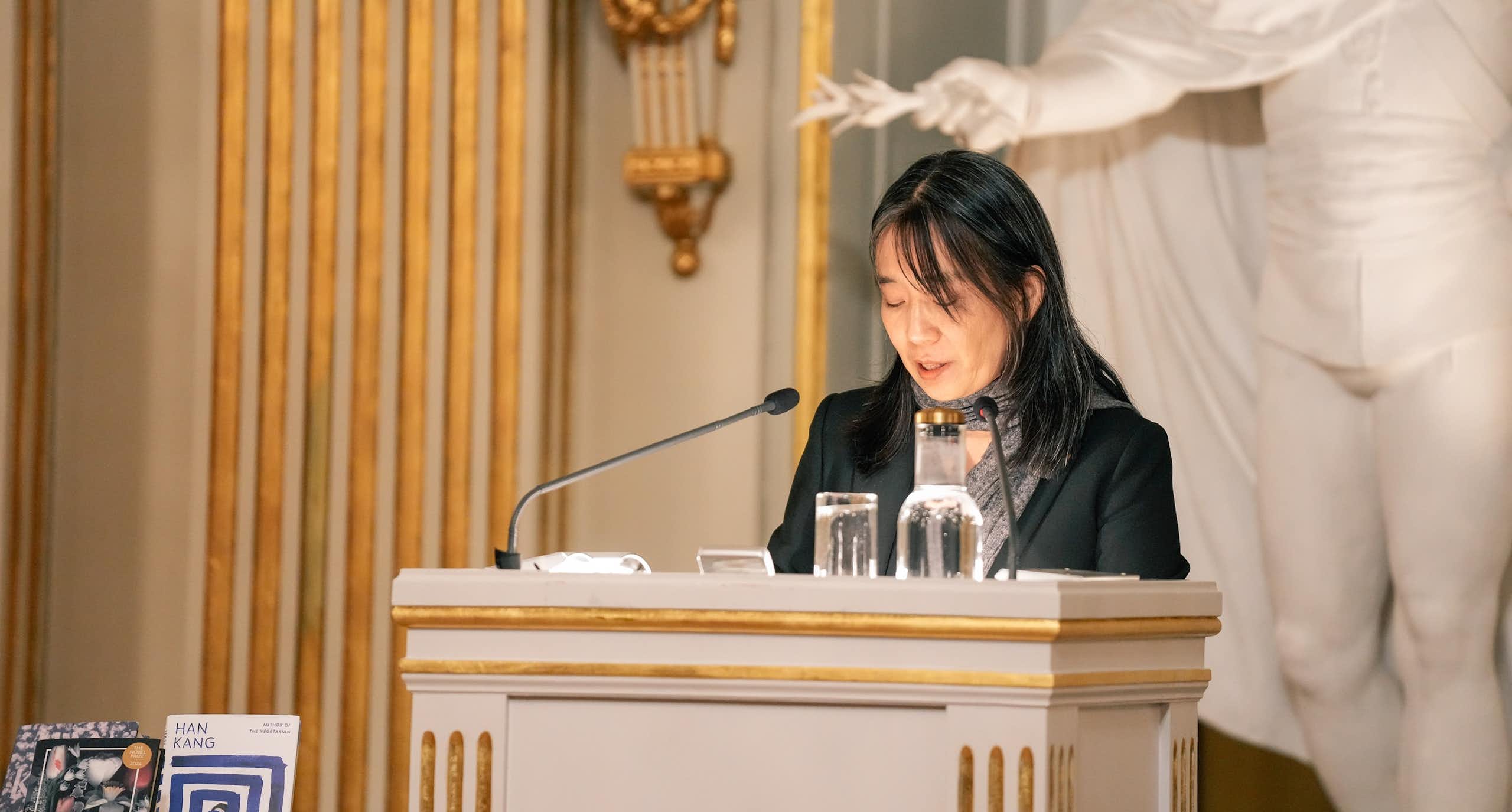 Una mujer ante un atril dando un discurso.