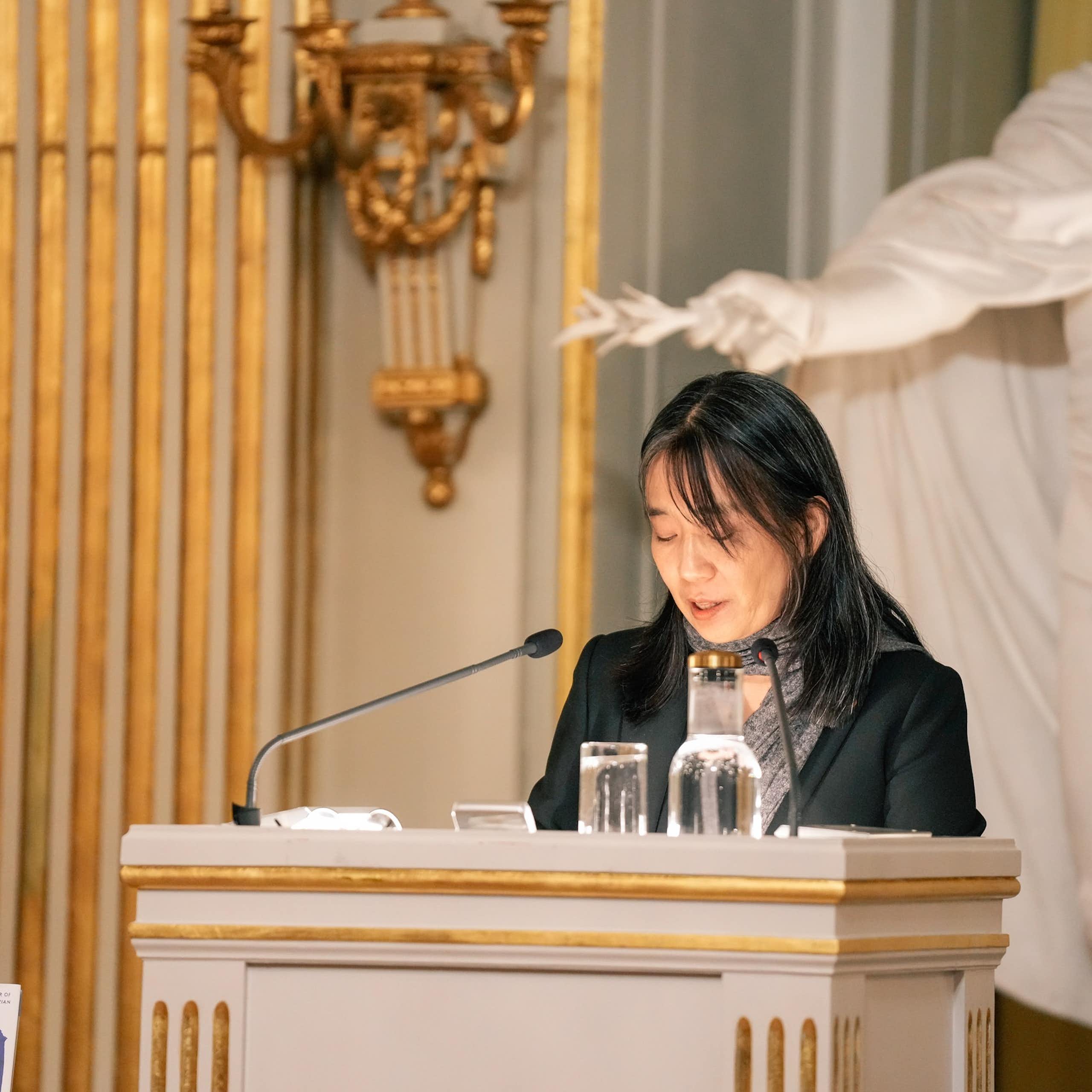 Una mujer ante un atril dando un discurso.