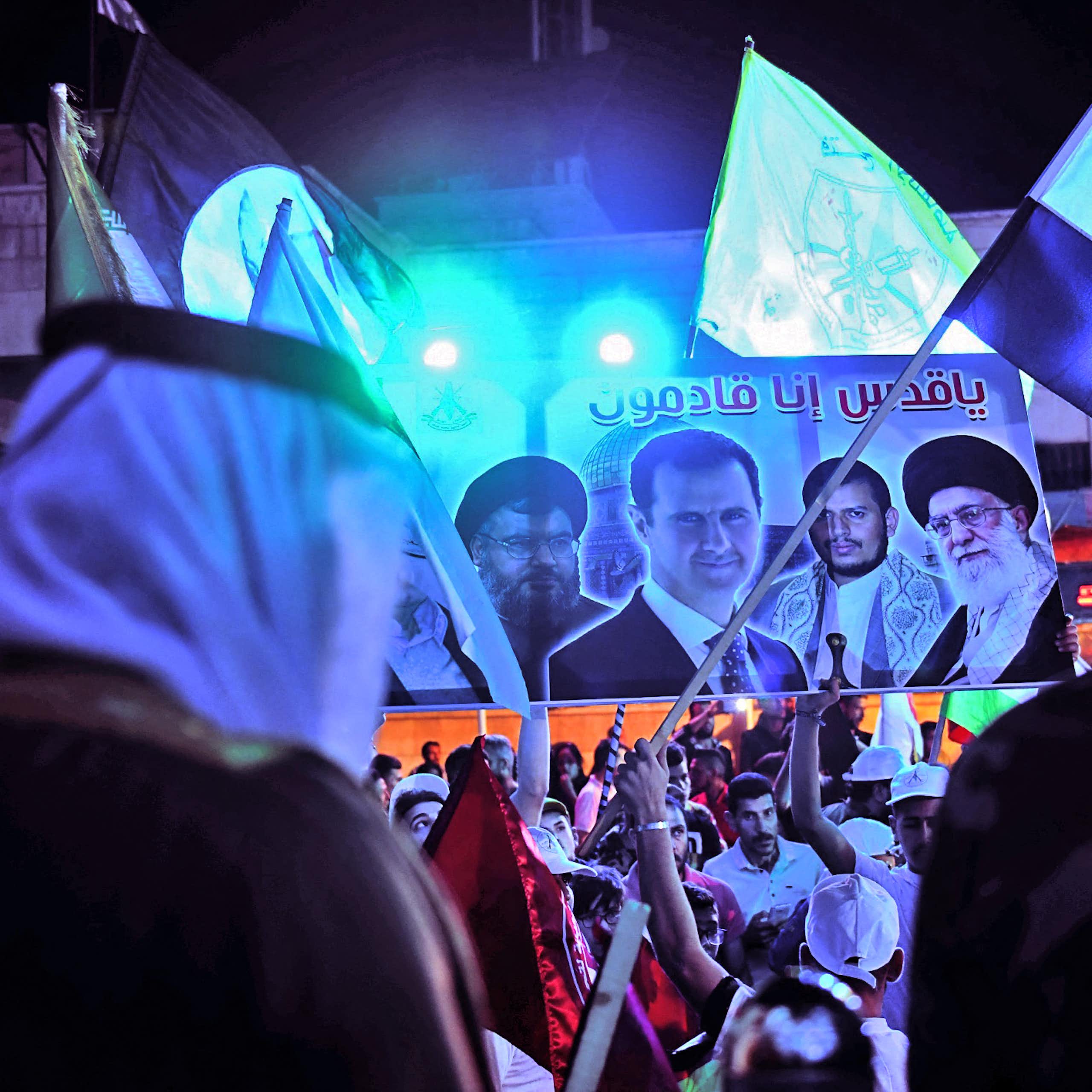 Men wave flags and a banner showing the face of four men.