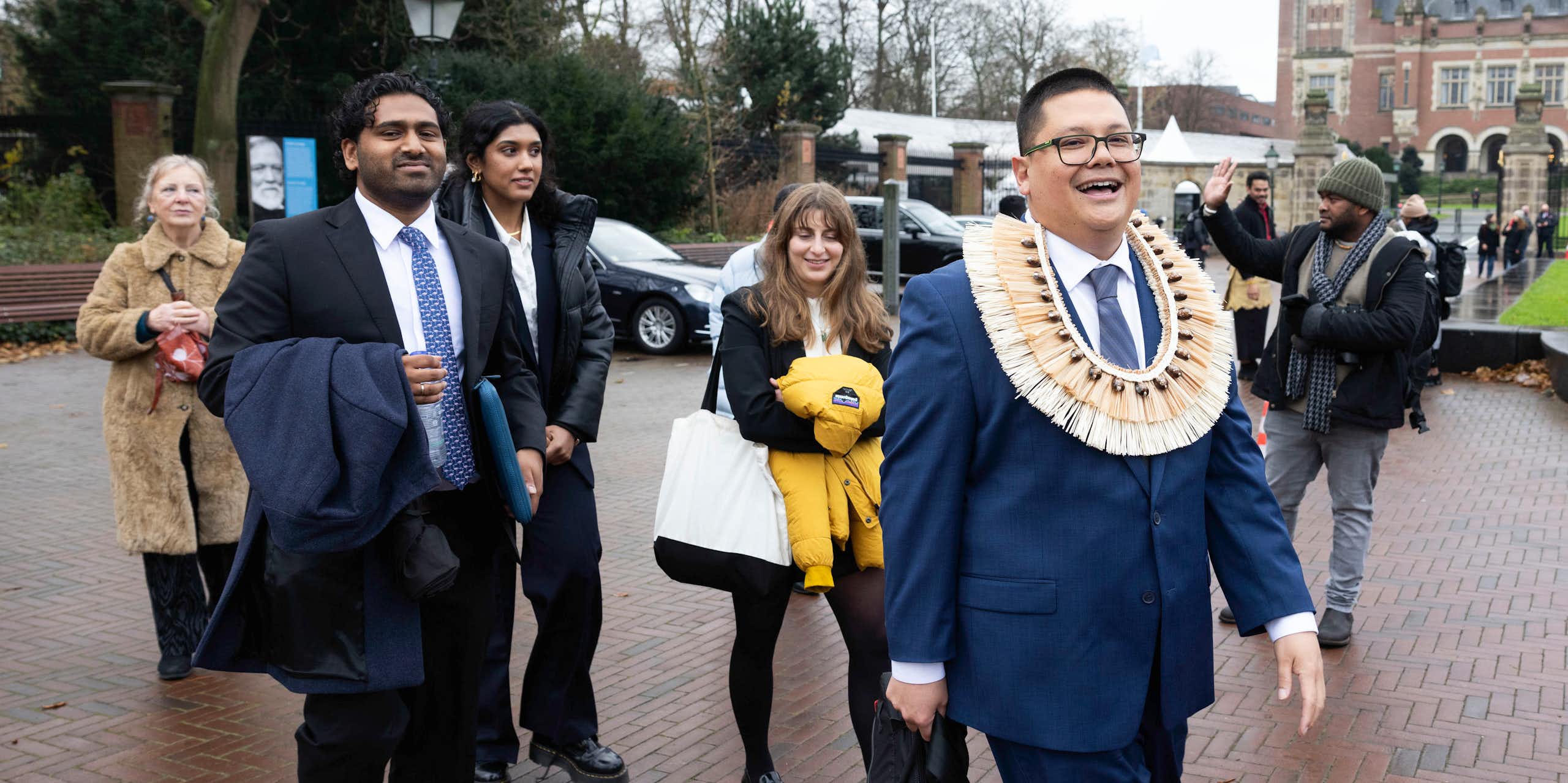 A lawyer with a traditional Vanuatu grass band around his neck leaves the ICJ with his legal team