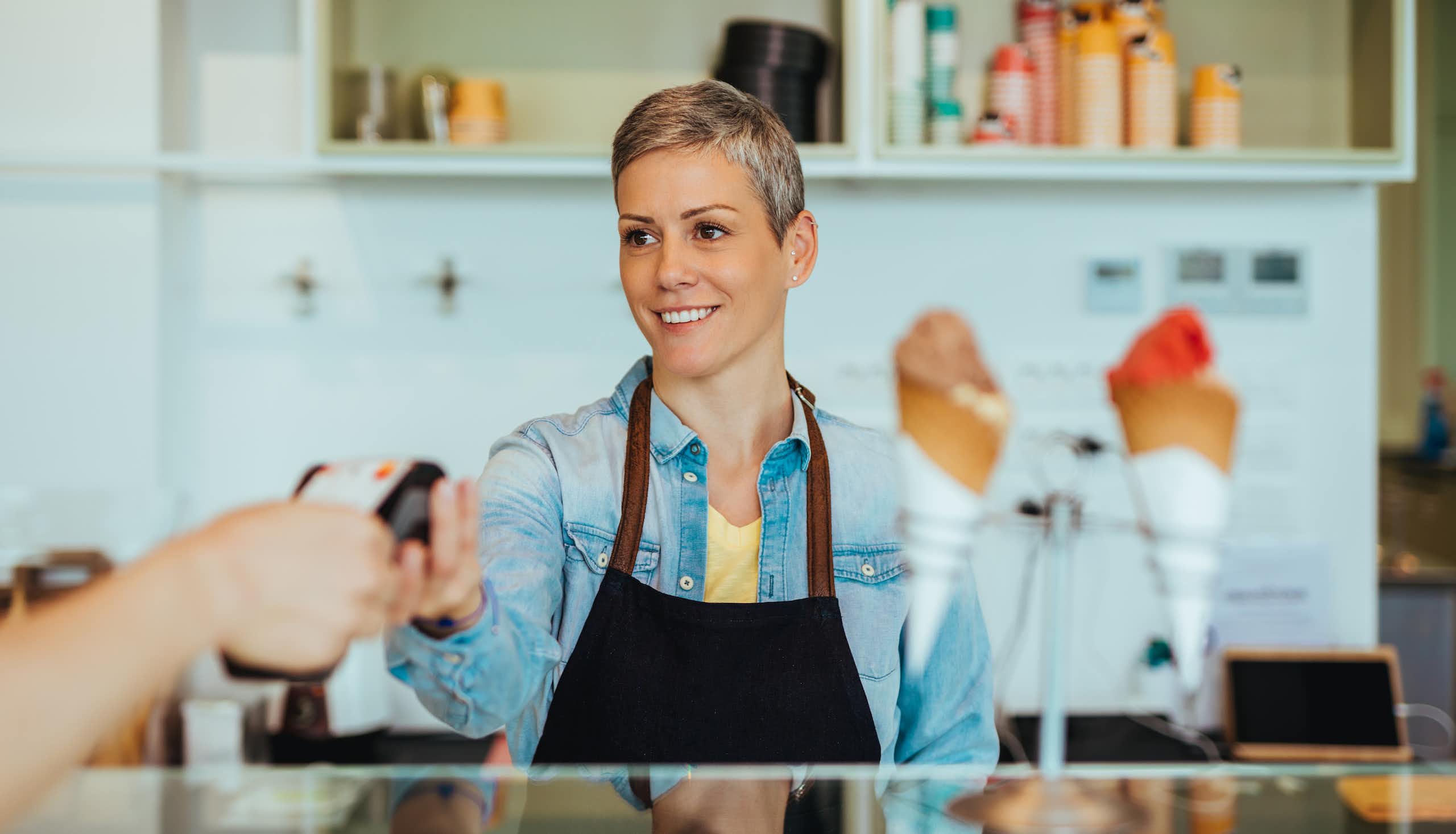 Woman standing behind a counter serving icecream