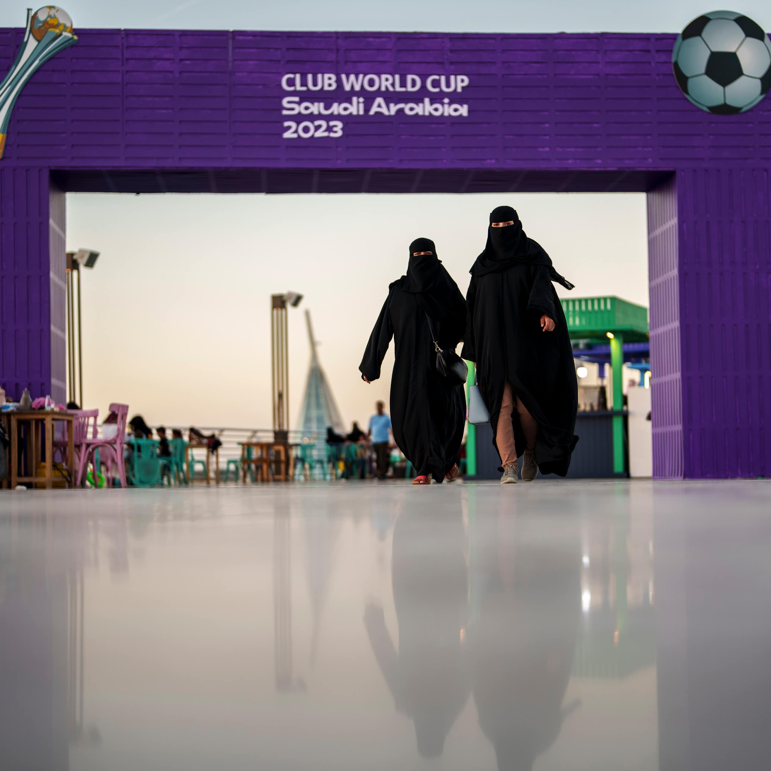 Women walk in front of a fan zone during the Soccer Club World Cup in Saudi Arabia, 2023.