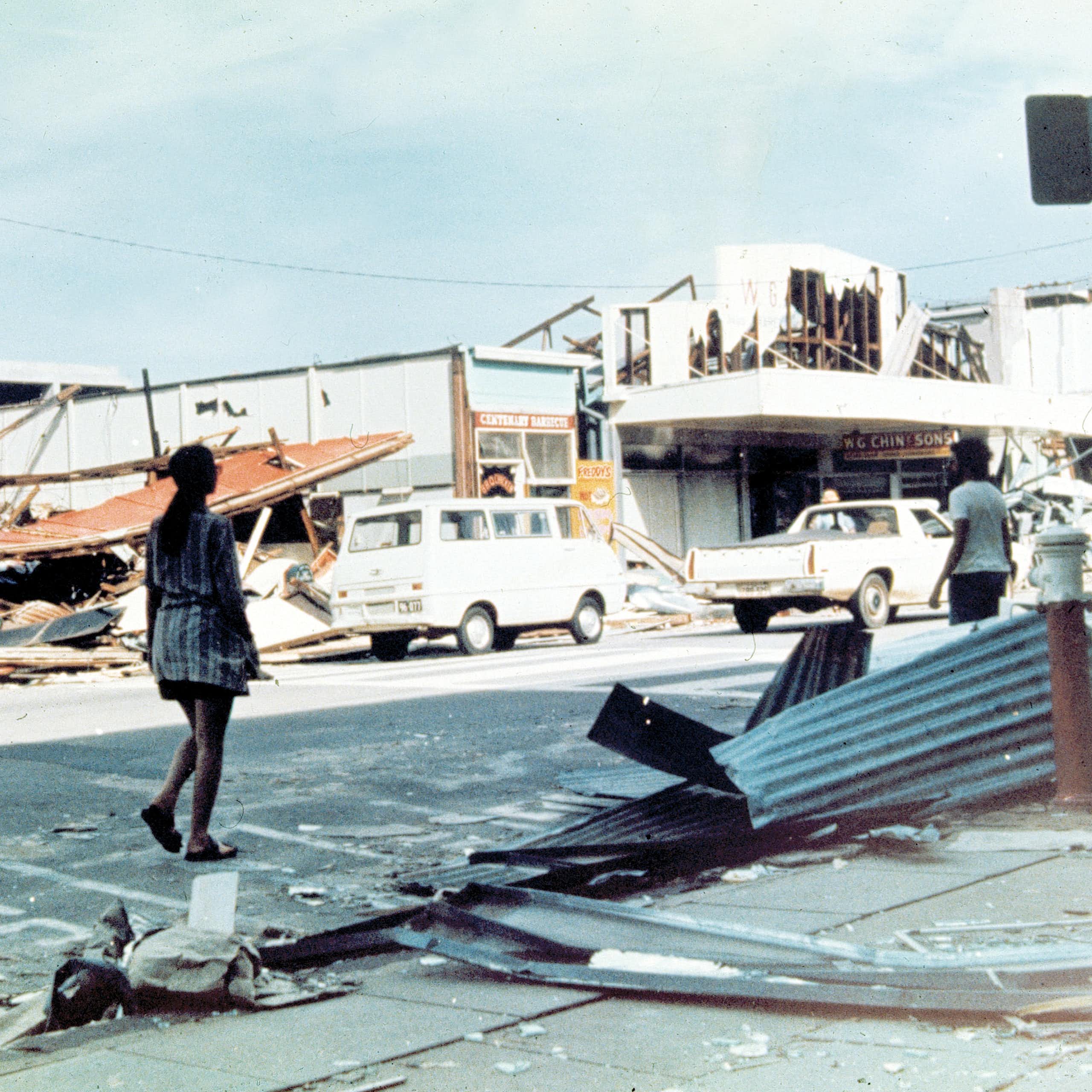 woman walks along damaged street