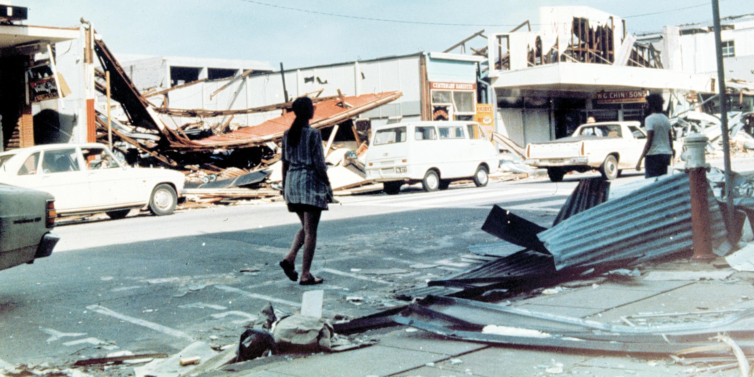 woman walks along damaged street