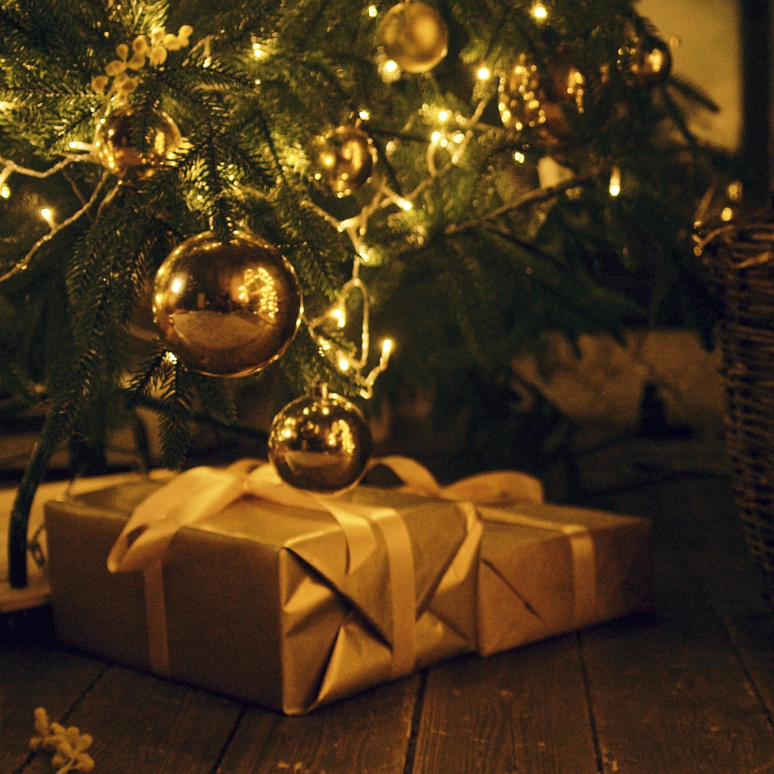 des cadeaux au pied d'un sapin de noël. la lumière est dorée.
