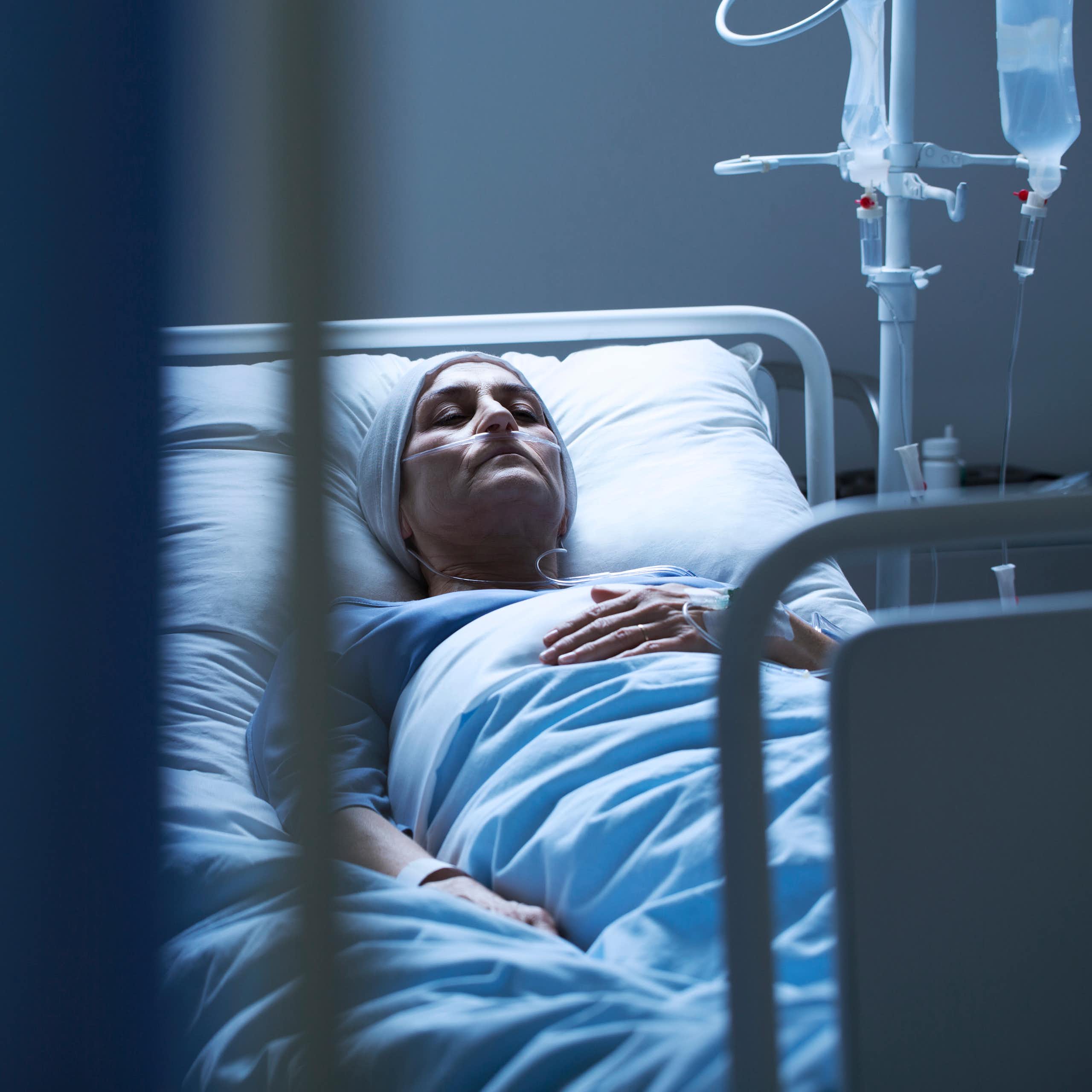 A woman with a head covering sleeping in a hospital bed.