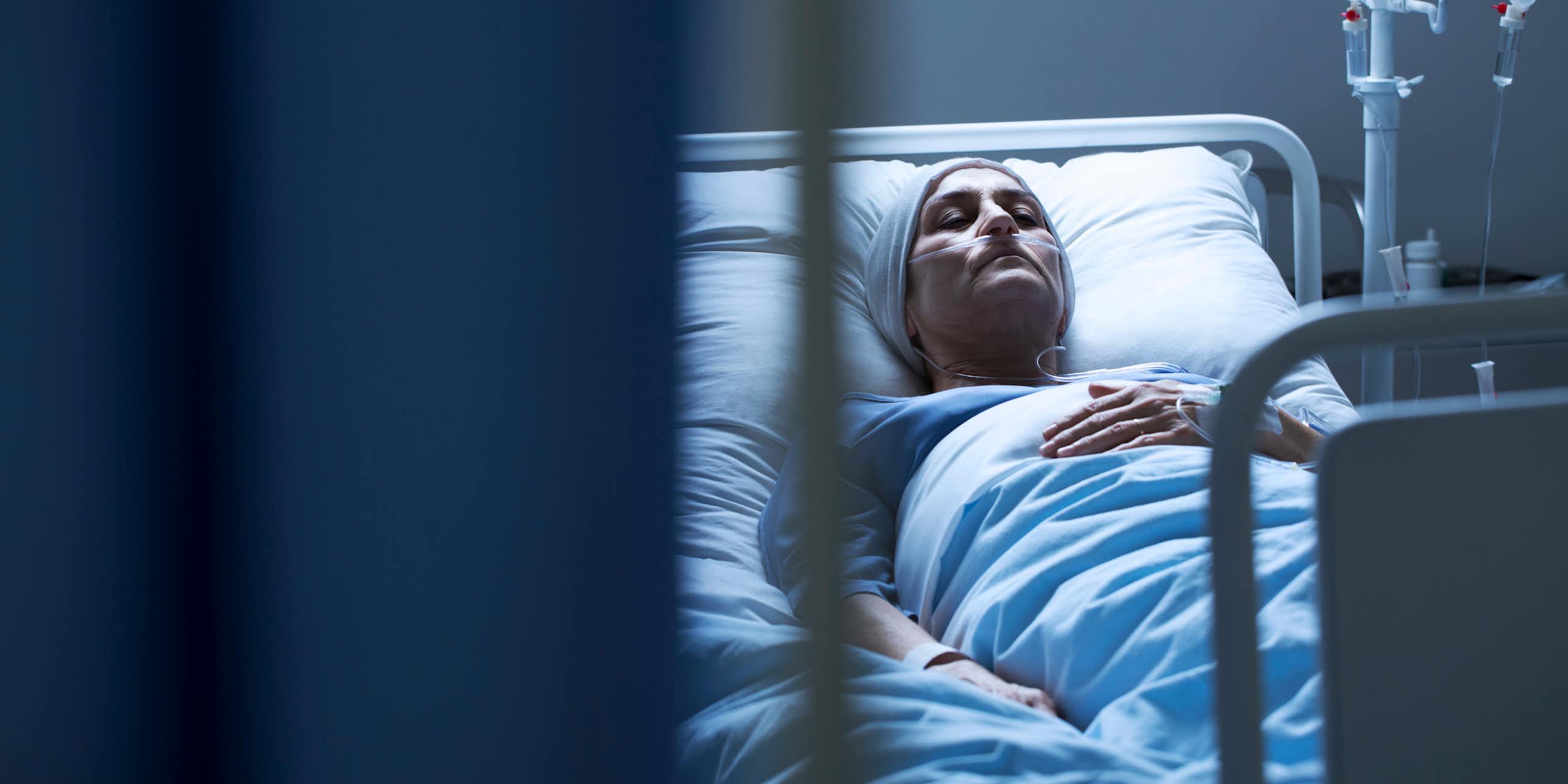 A woman with a head covering sleeping in a hospital bed.