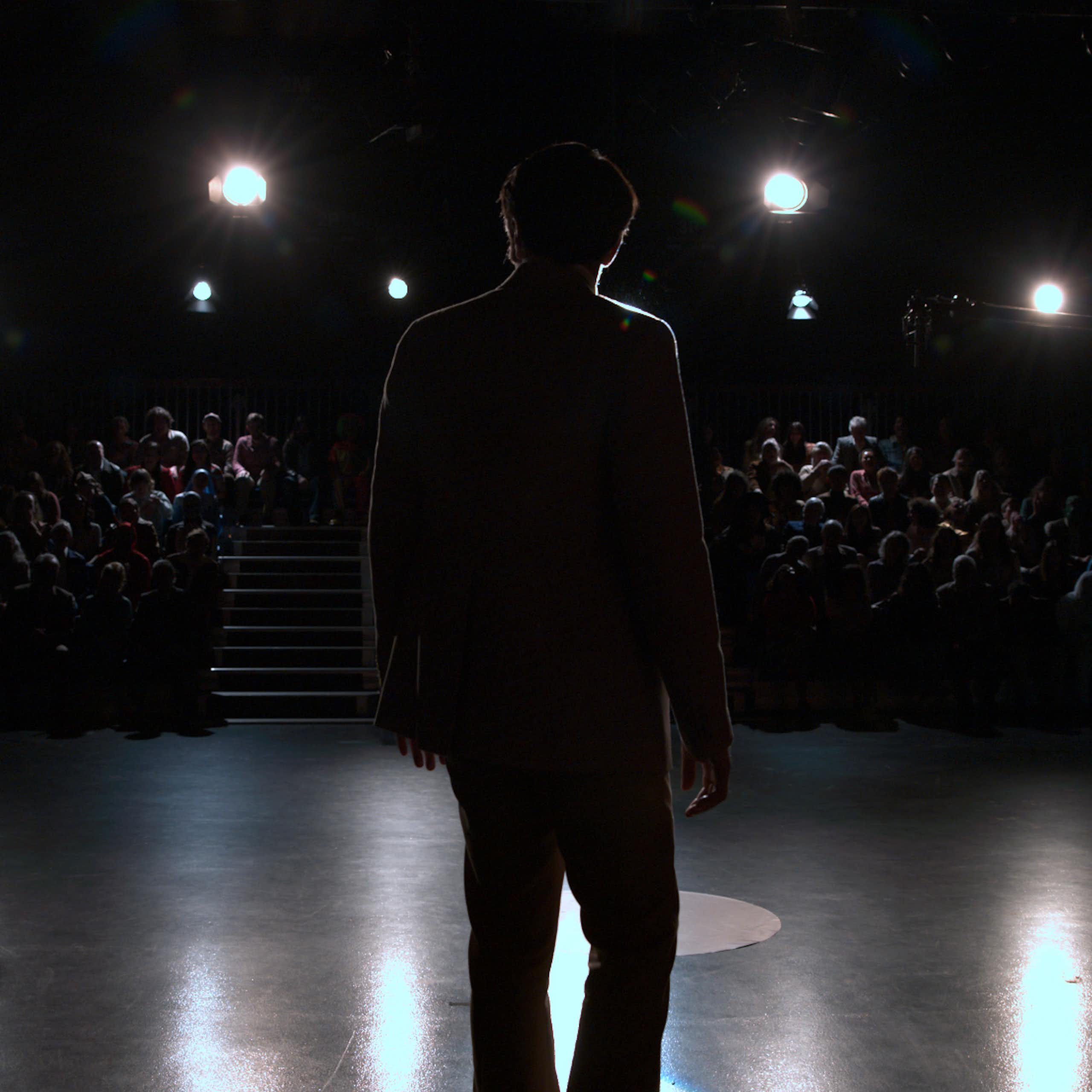 A man in silhouette in front of an audience.  