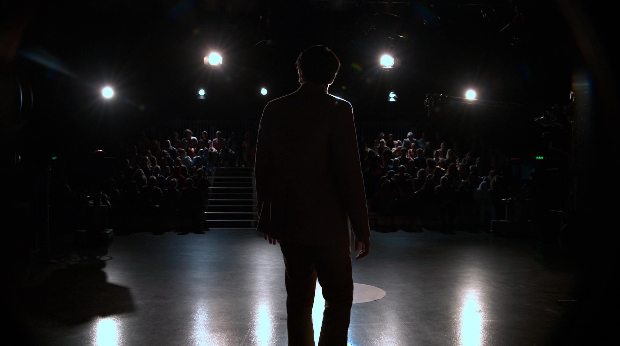 A man in silhouette in front of an audience.  
