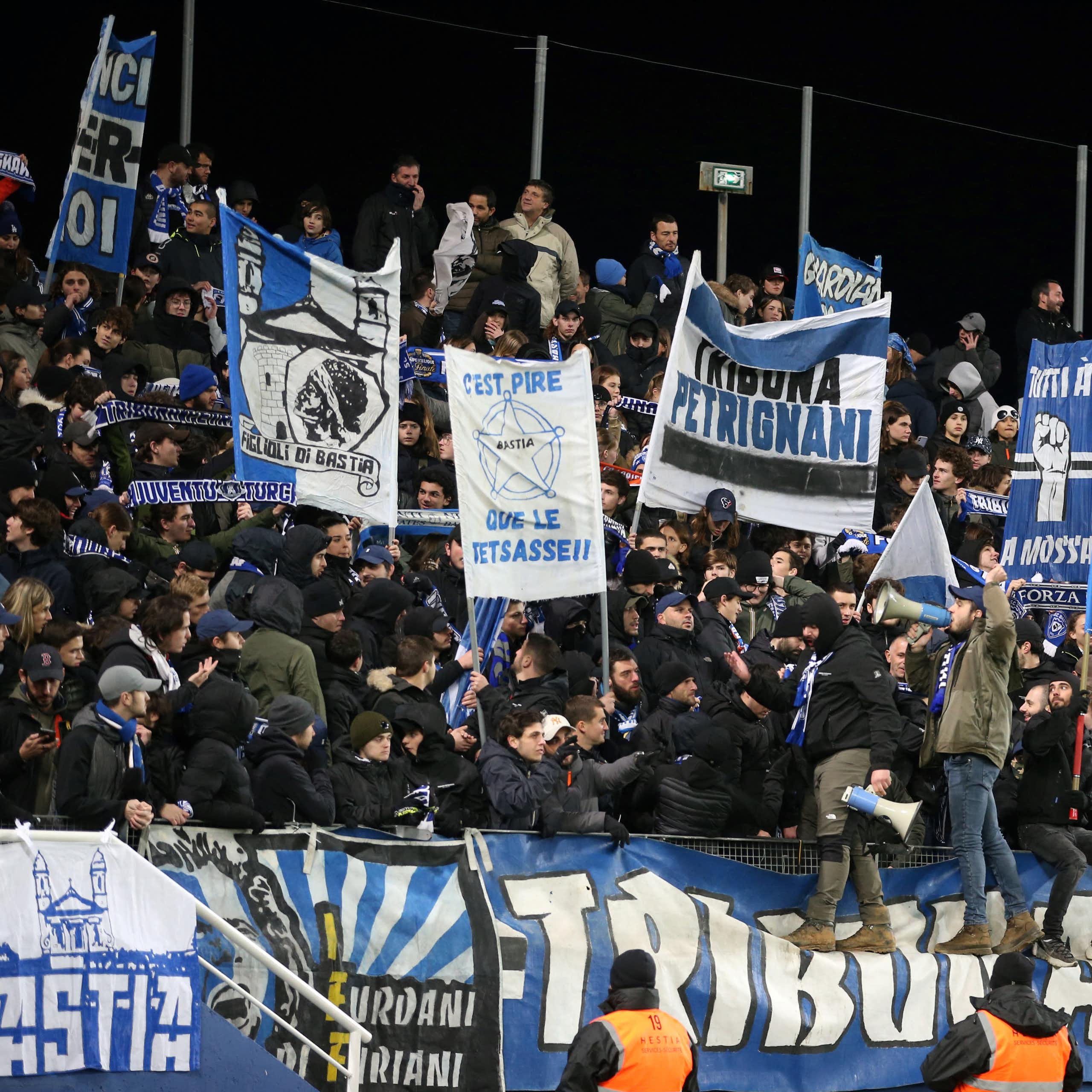 Des supporters agitent des drapeaux depuis les tribunes d'un match de football.